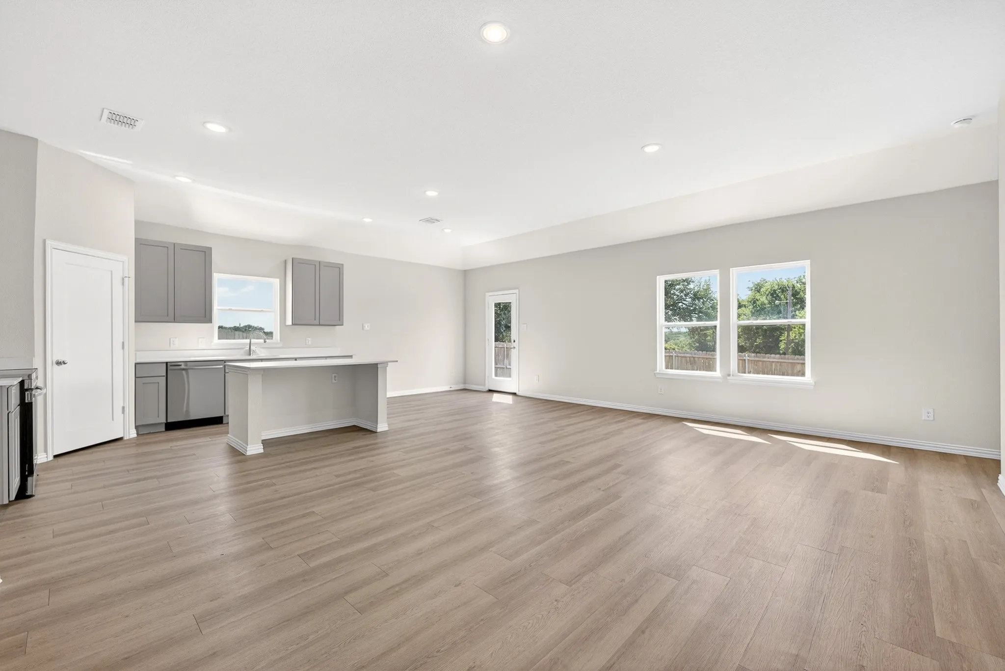 Open-concept living area featuring wood-finish flooring, recessed lighting, and multiple windows