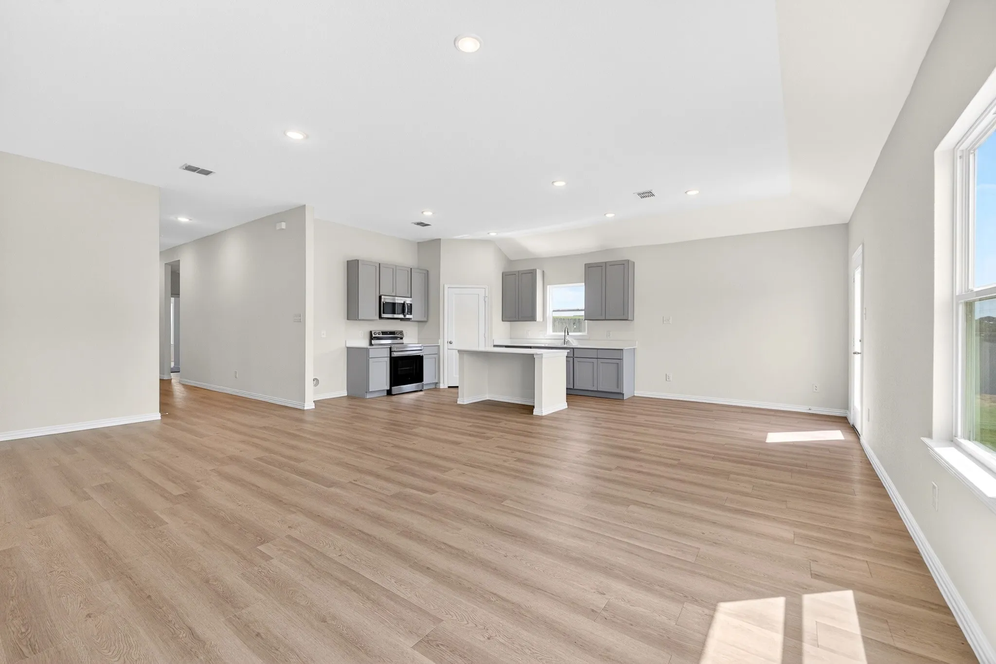 Expansive main living area featuring wood-finish flooring, recessed lighting, and vaulted ceilings