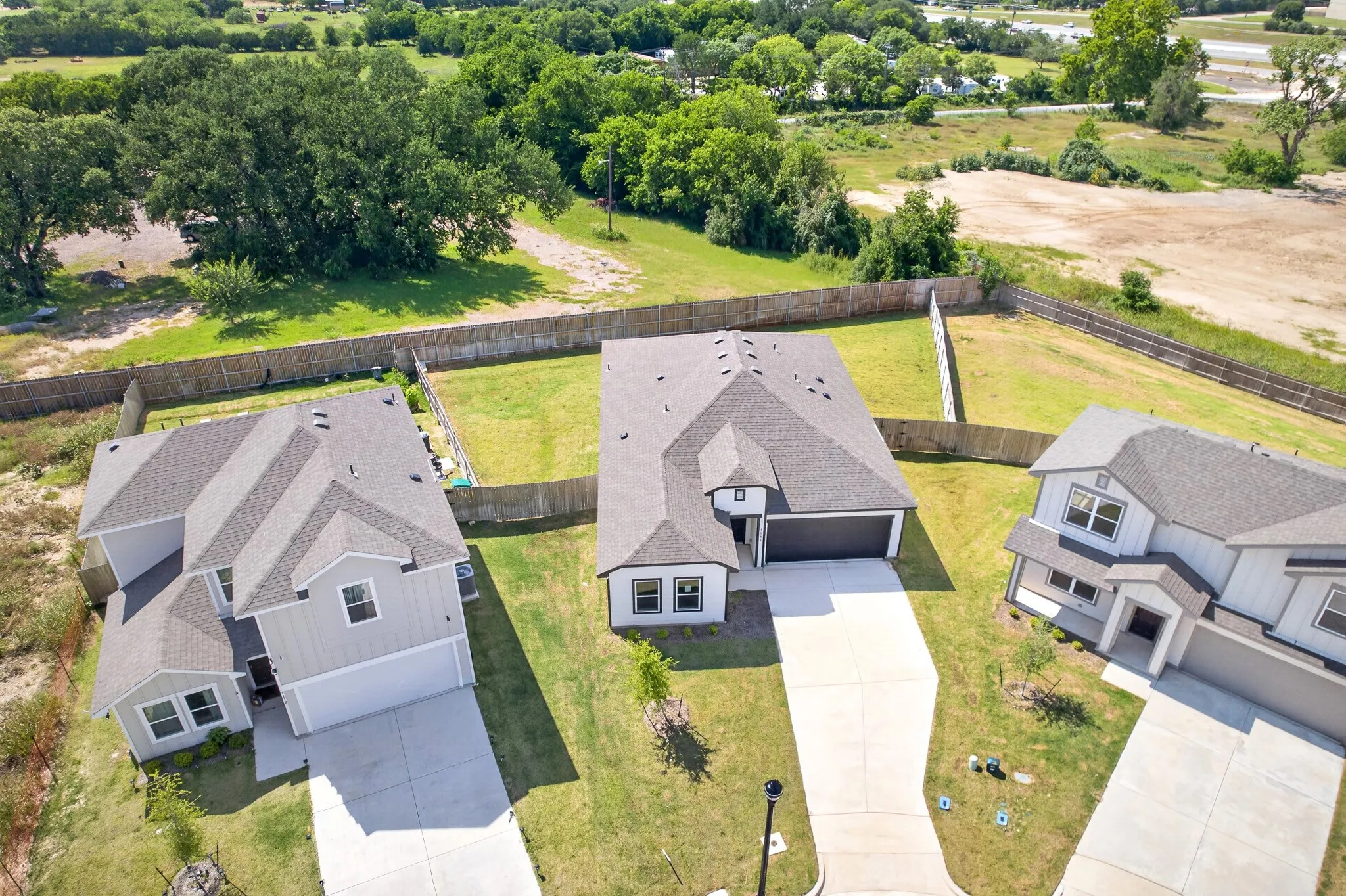 Contemporary residence with a dark gray shingle roof, light-colored siding, and an attached two-car garage