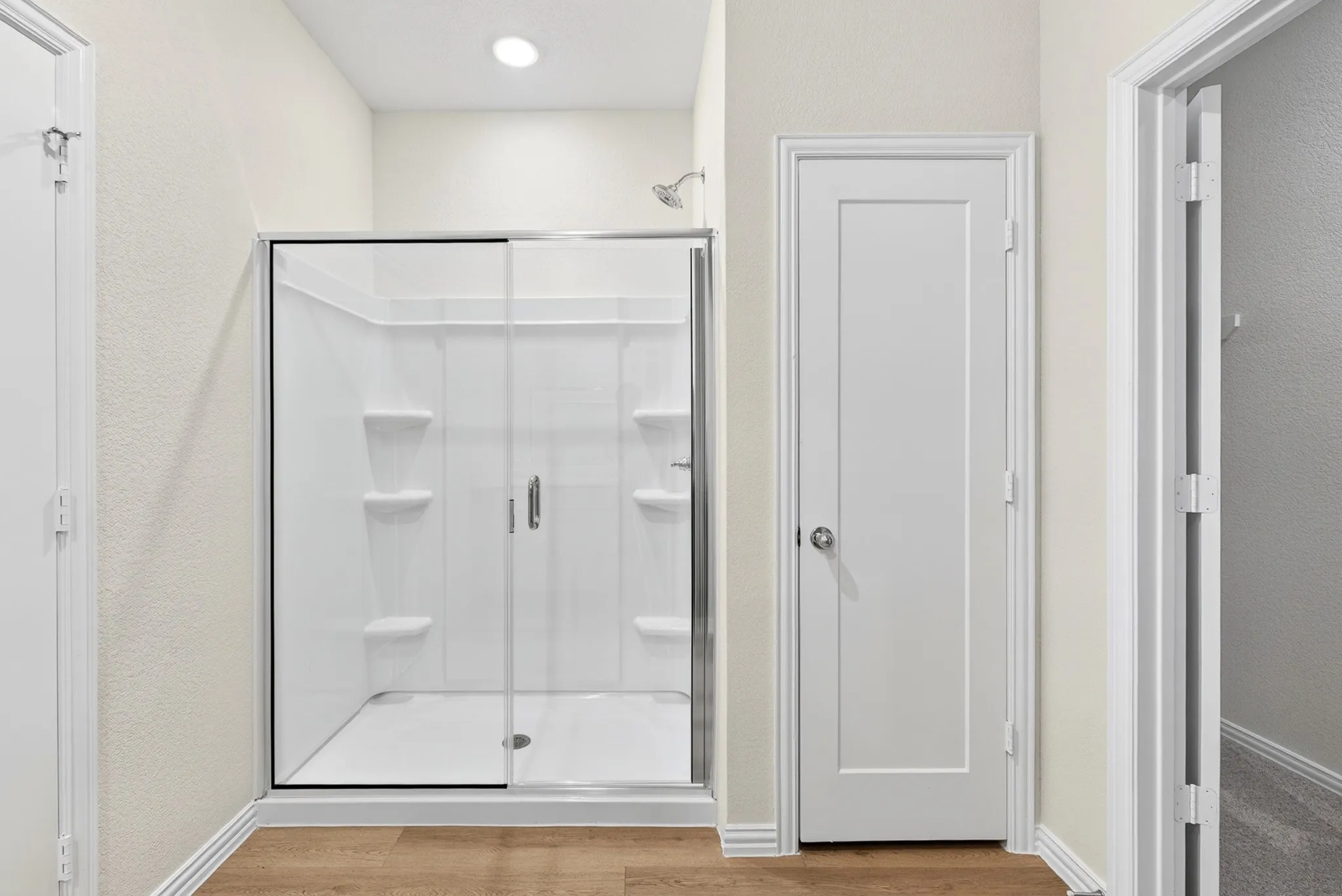 Walk-in shower with a glass enclosure and built-in shelving