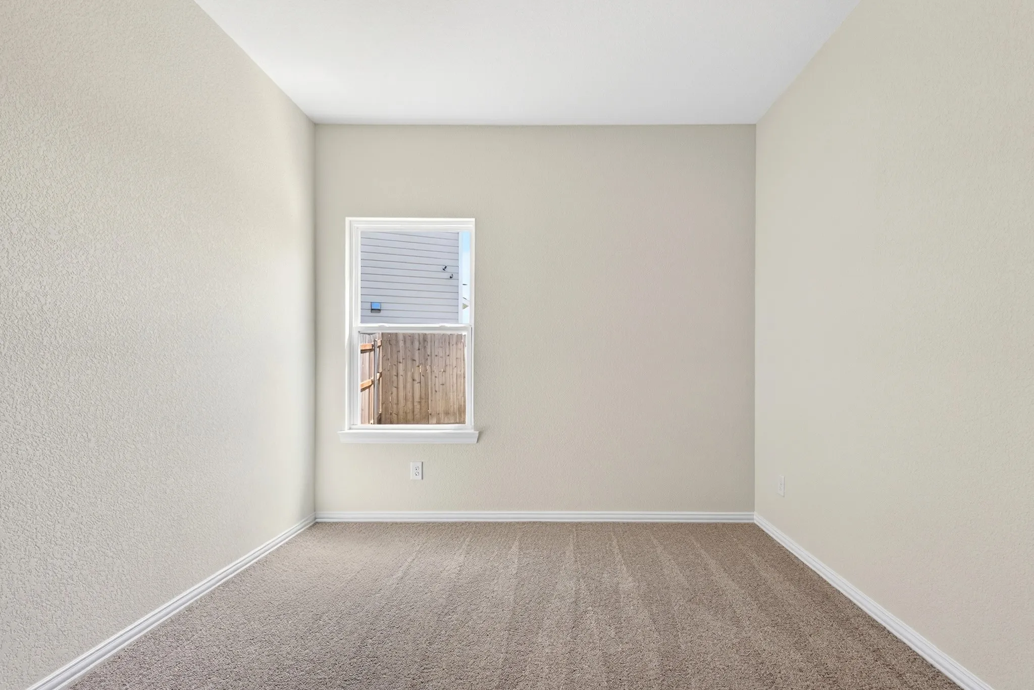 Neutral-toned wall finishes with a single window and light-colored carpeting