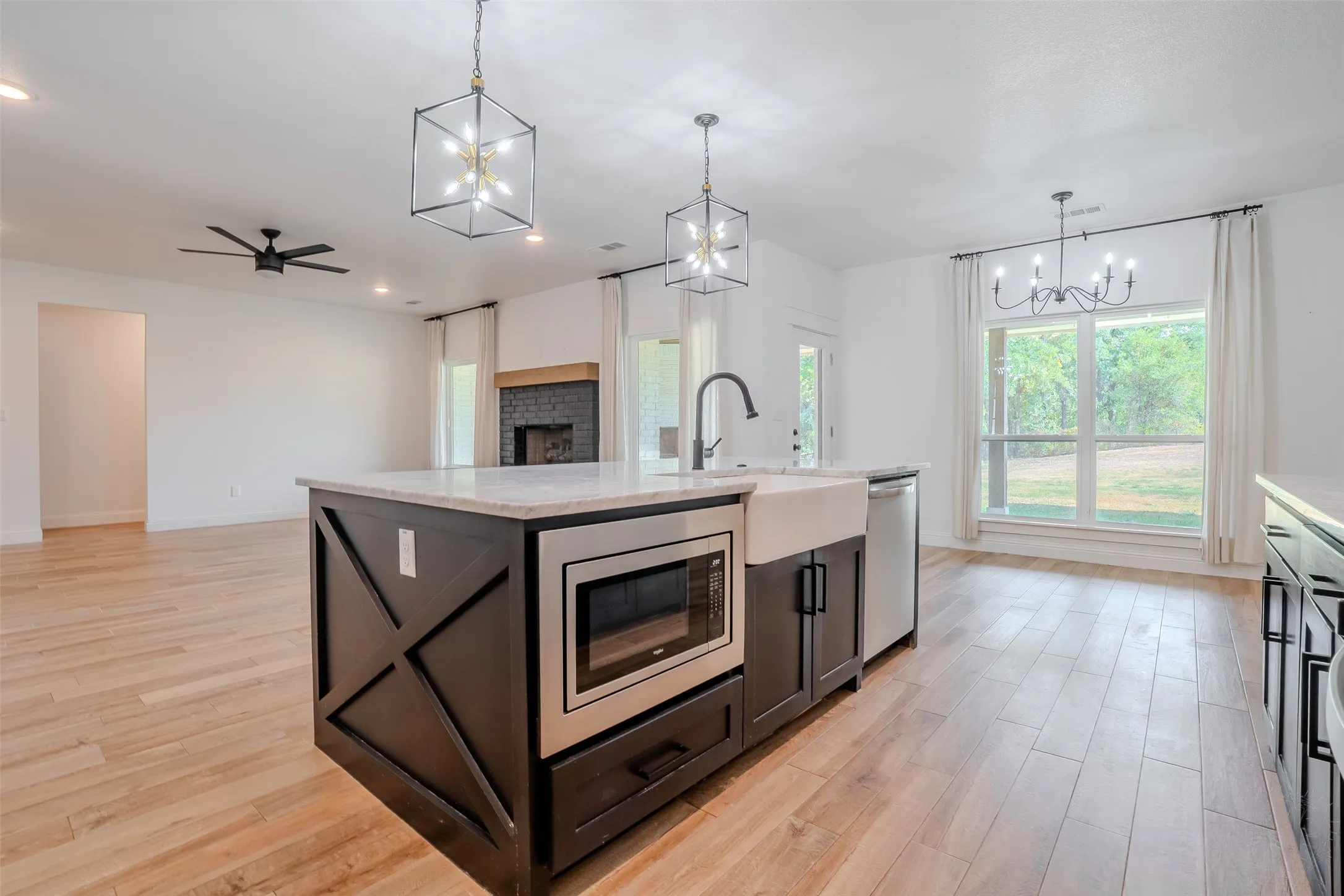 Kitchen island with built-in microwave, farmhouse sink, and white granite countertop