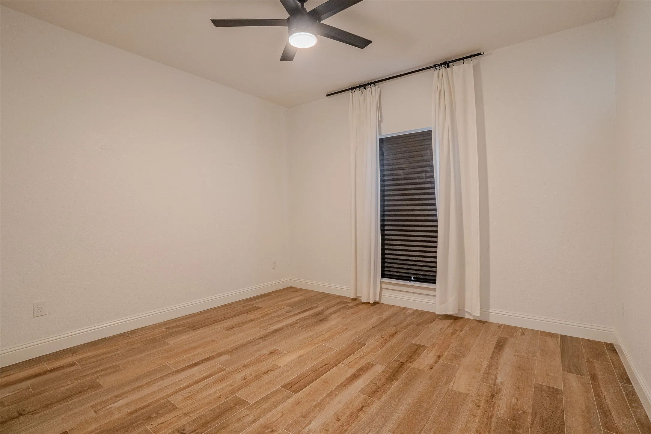 Bedroom #1, Wood-look tile flooring, white walls, window with blinds, and a ceiling fan with integrated lighting