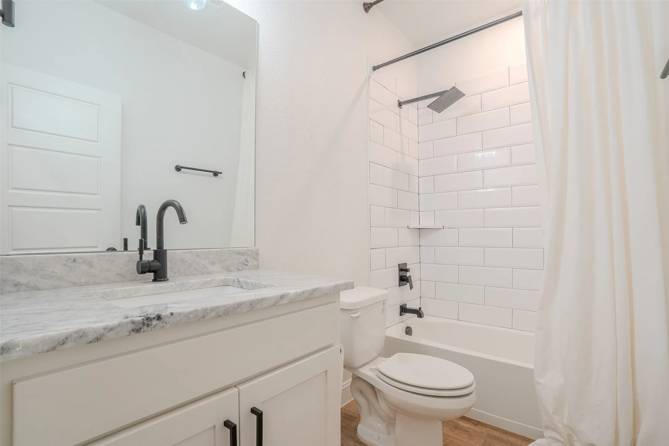 Full Bathroom next to Bedroom #1. Featuring Vanity with white granite countertop and an undermount sink. Matte Black fixtures.