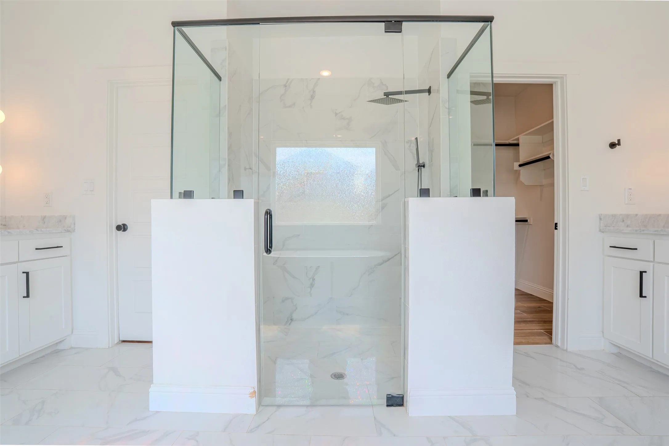 Glass-enclosed shower with a rainfall showerhead, Shower wand, integrated bench seating, and patterned tile surround