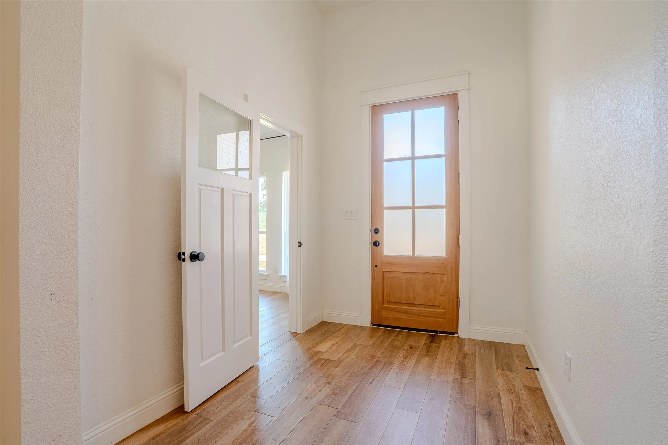 Entry way with tall ceilings, tons of natural light, and tasteful wood-look tile floors throughout the home. The office/flex room located off to the left.