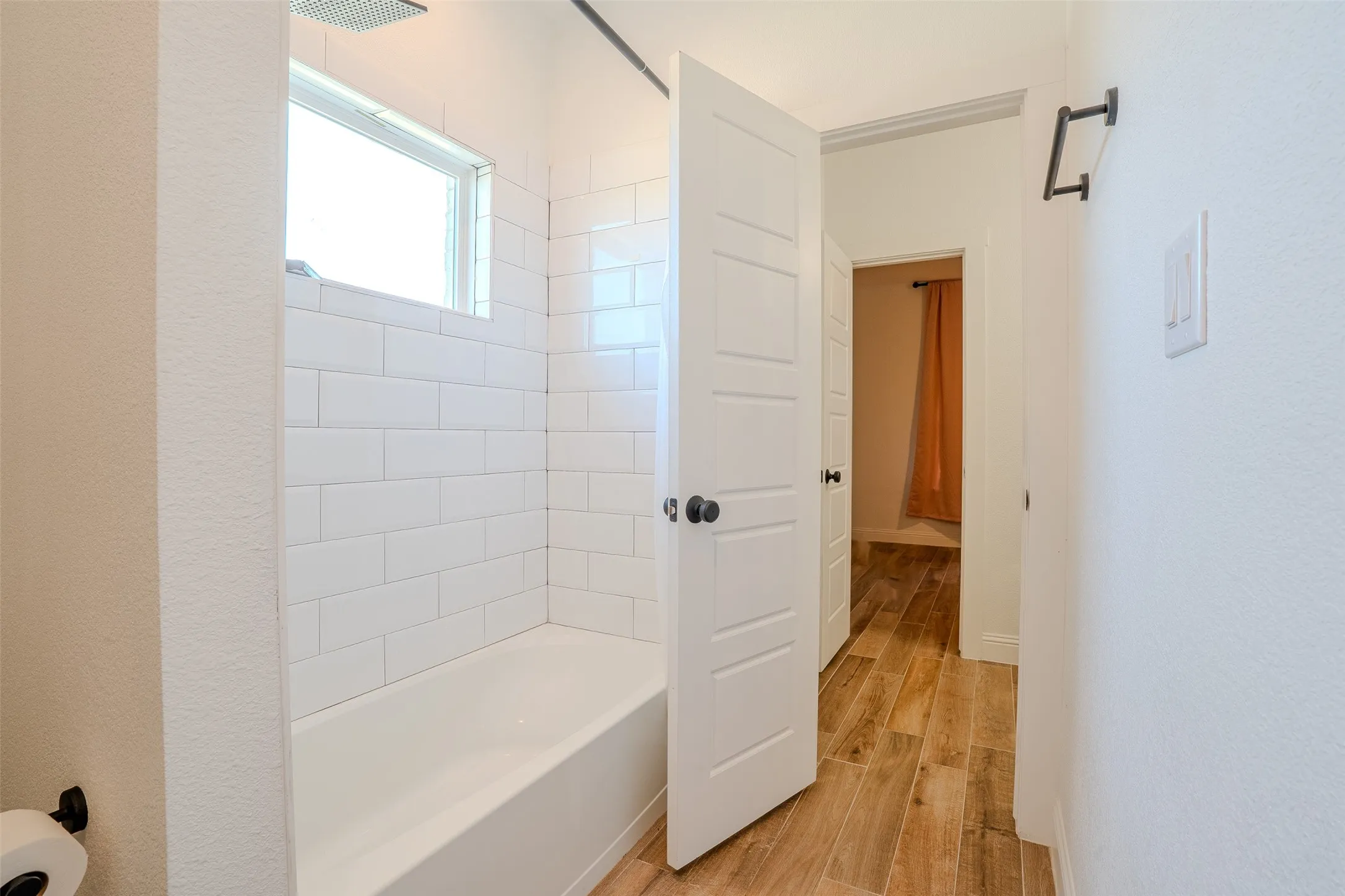 Jack and Jill bathroom with Bedroom #3 in the background. Bathtub with white subway tile, window which provides exquisite lighting, and rainfall showerhead.