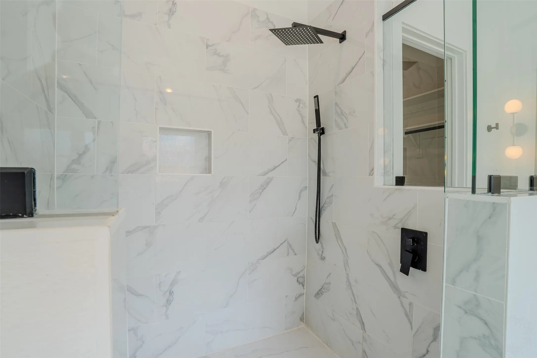 Glass-enclosed shower with a rainfall showerhead, Shower wand, integrated bench seating, and patterned tile surround