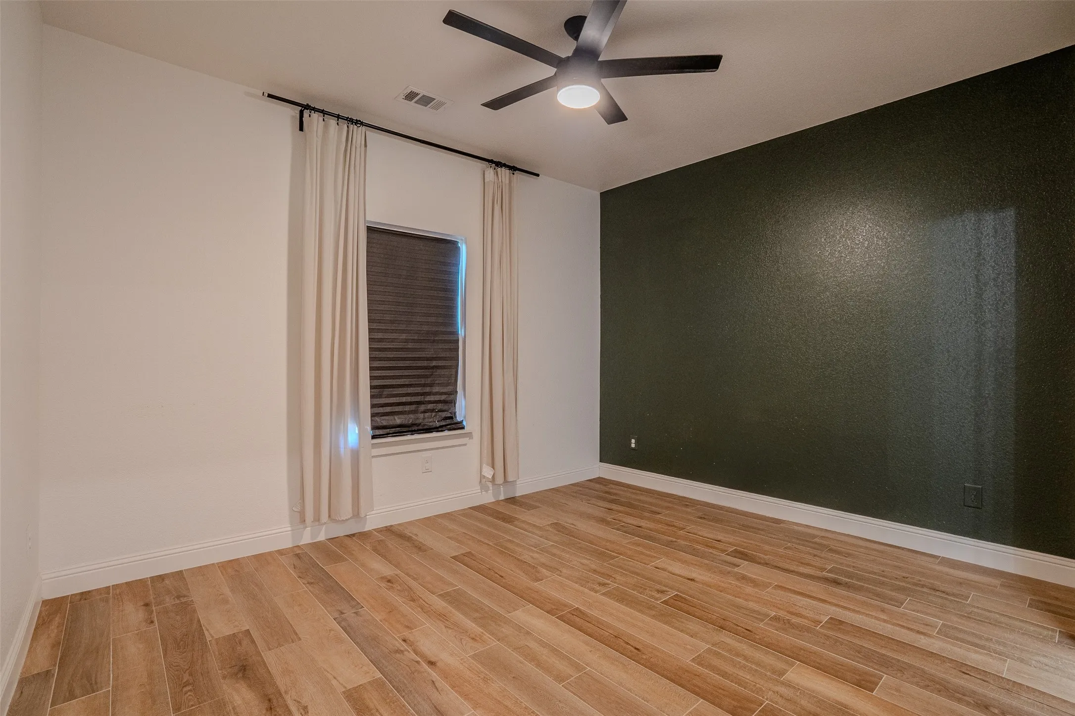 Bedroom #2. Wood-look Tile flooring, Dark Olive Green accent wall, window with blinds, ceiling fan with integrated lighting, and crown molding