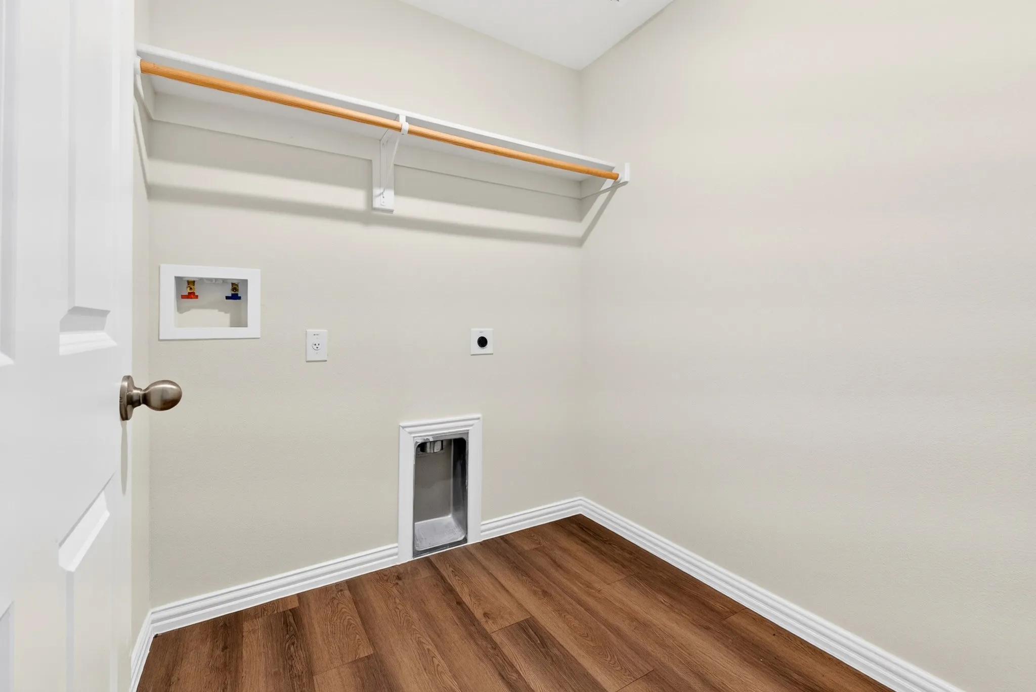 Laundry space featuring wood-finish flooring, a clothing rod, and a utility sink hookup