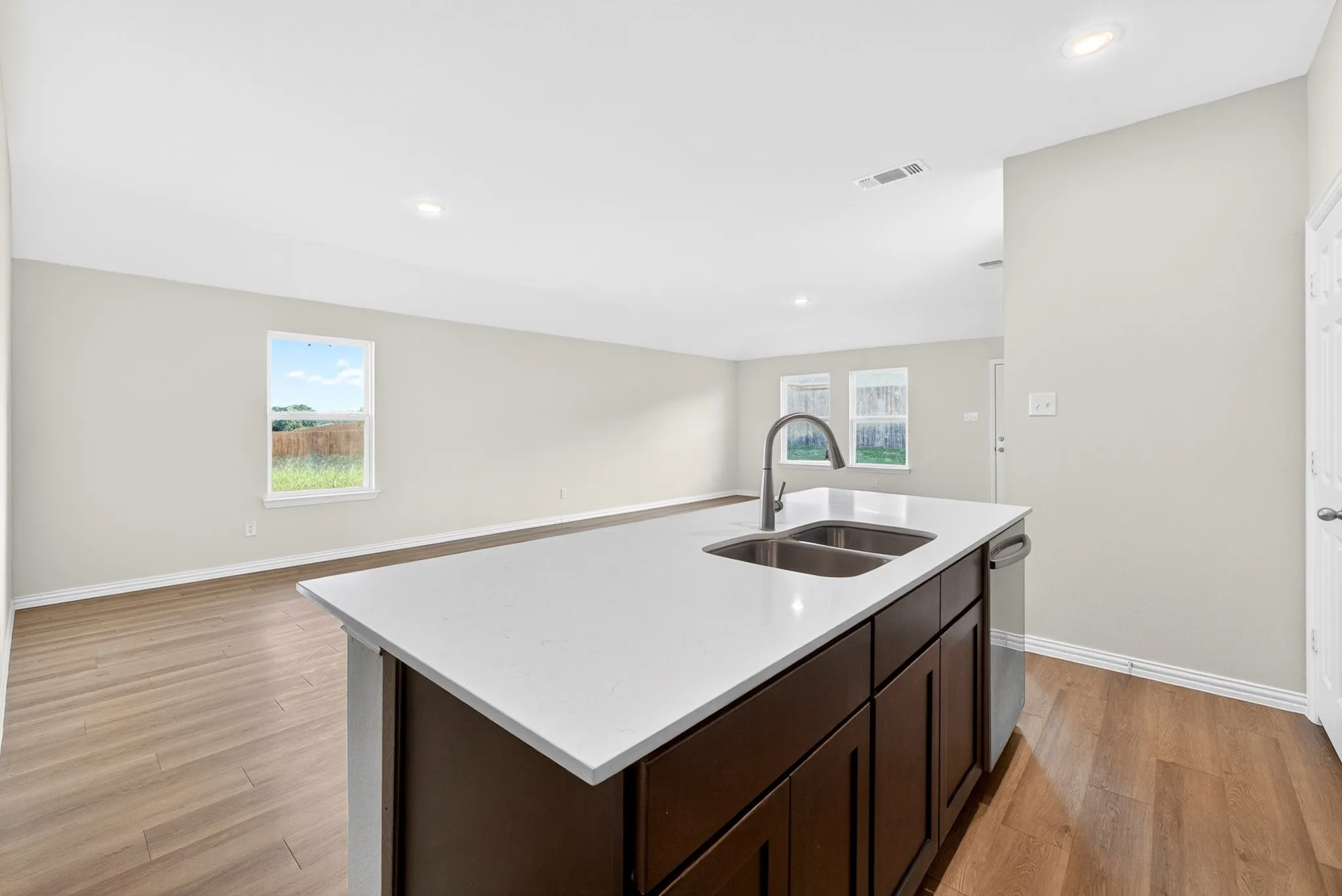 Kitchen island with a white countertop, double basin sink, and a gooseneck faucet