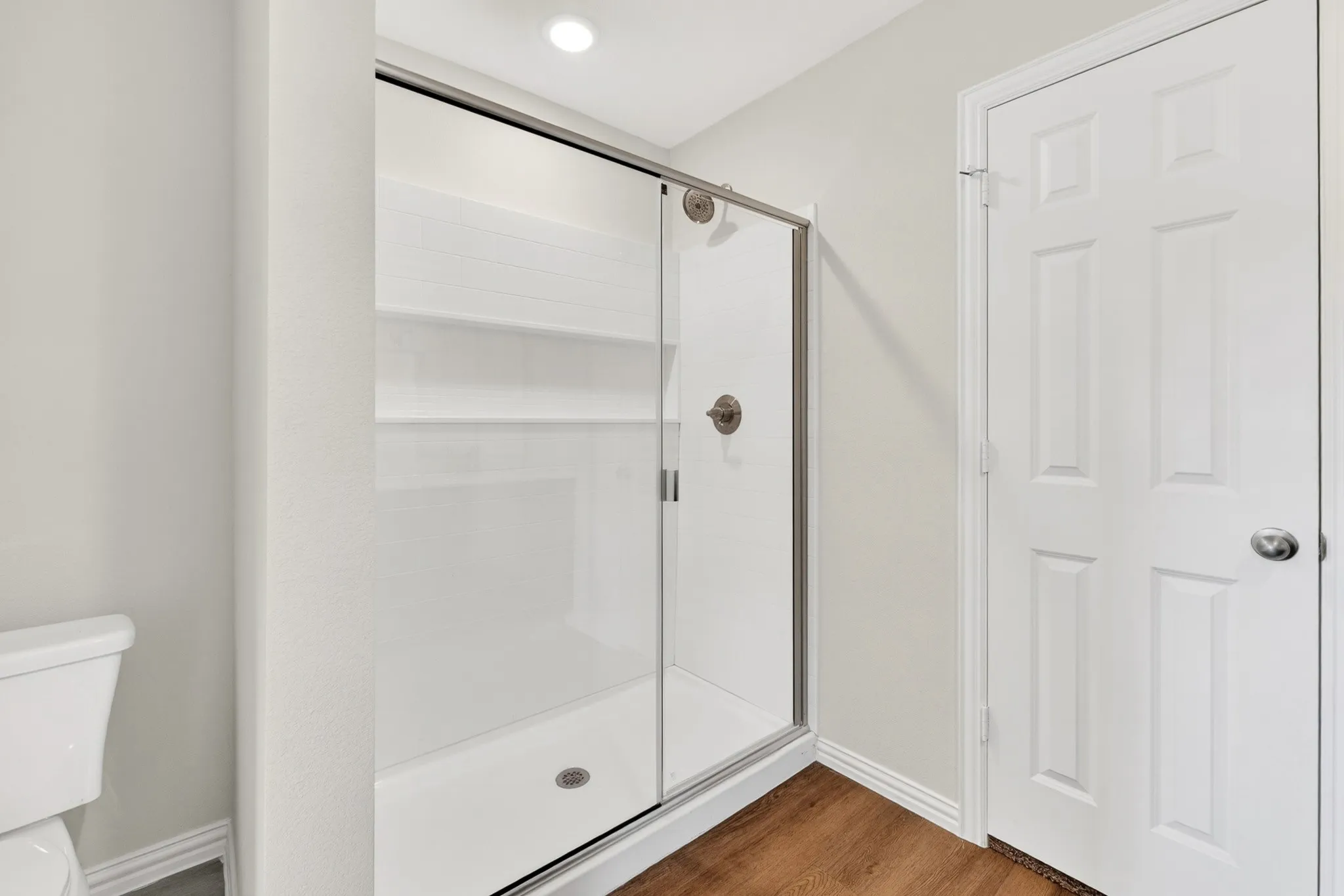 Shower enclosure with sliding glass doors, integrated shelving, and brushed nickel fixtures