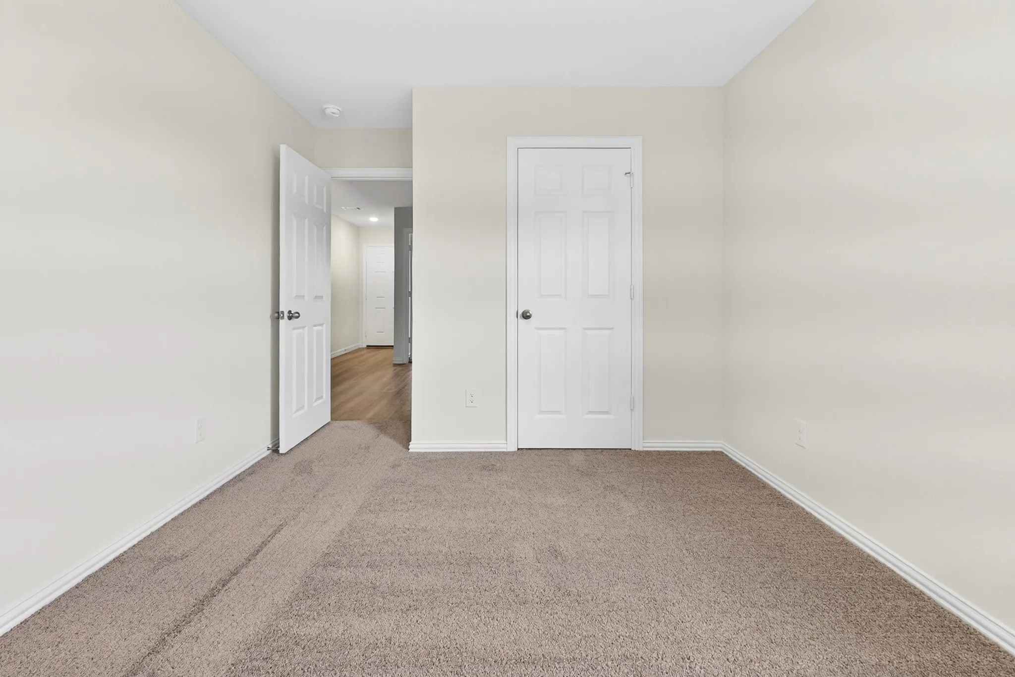 Neutral-toned walls complement the plush carpet flooring