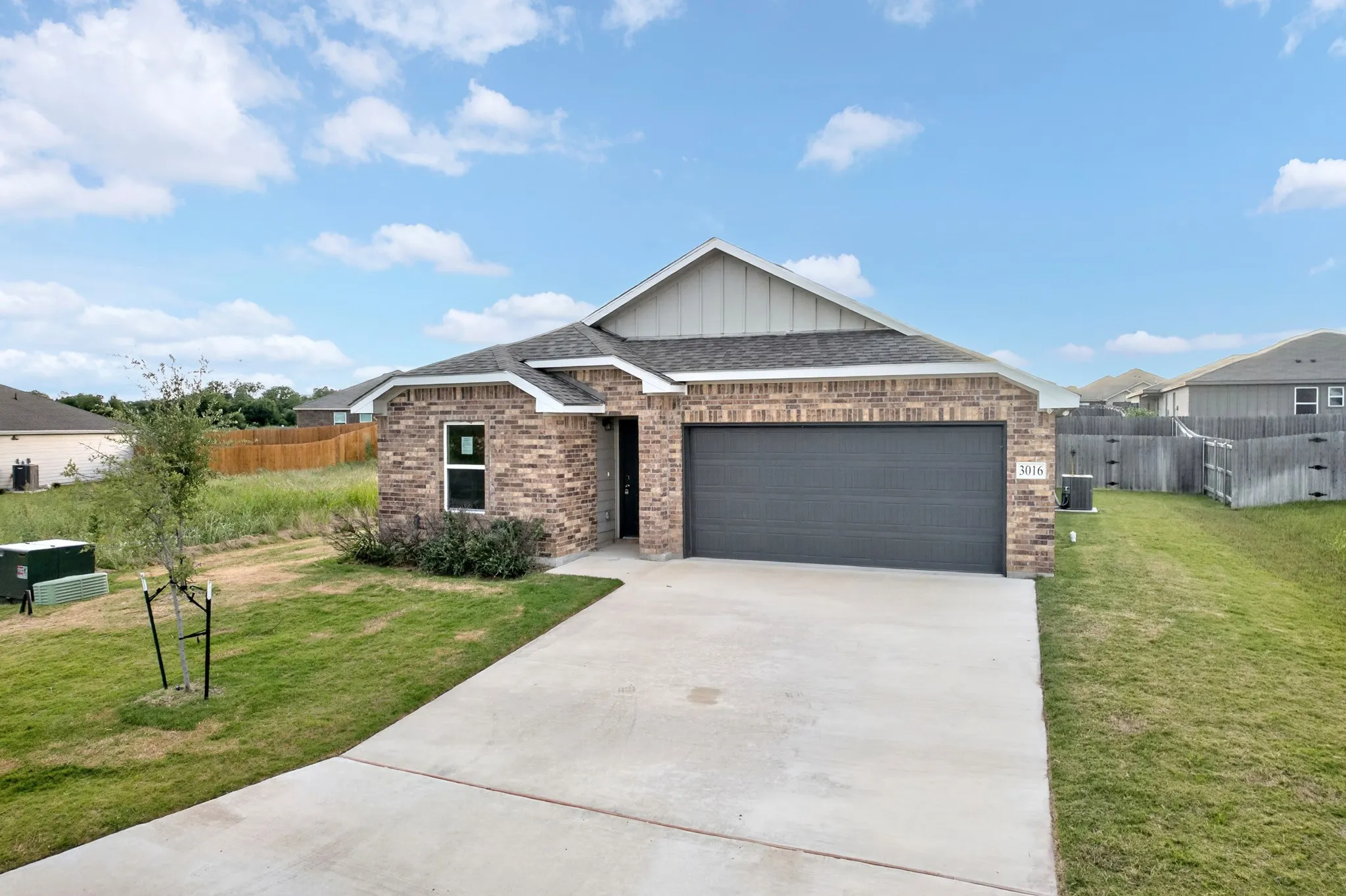 Brick veneer exterior, covered entry, attached garage, concrete driveway, and gabled roofline