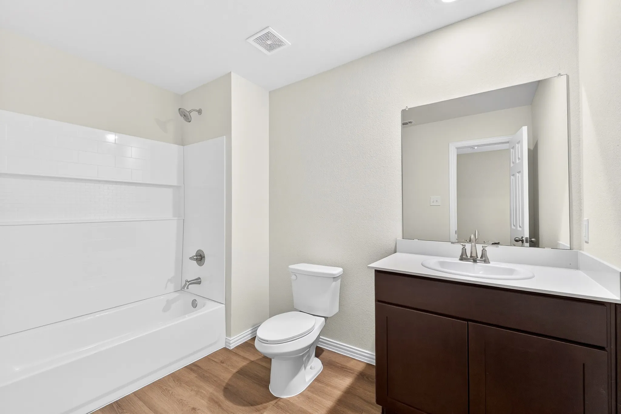 Spa-inspired bathroom featuring a dark wood vanity with white marble countertop, chrome fixtures, and an oversized framed mirror