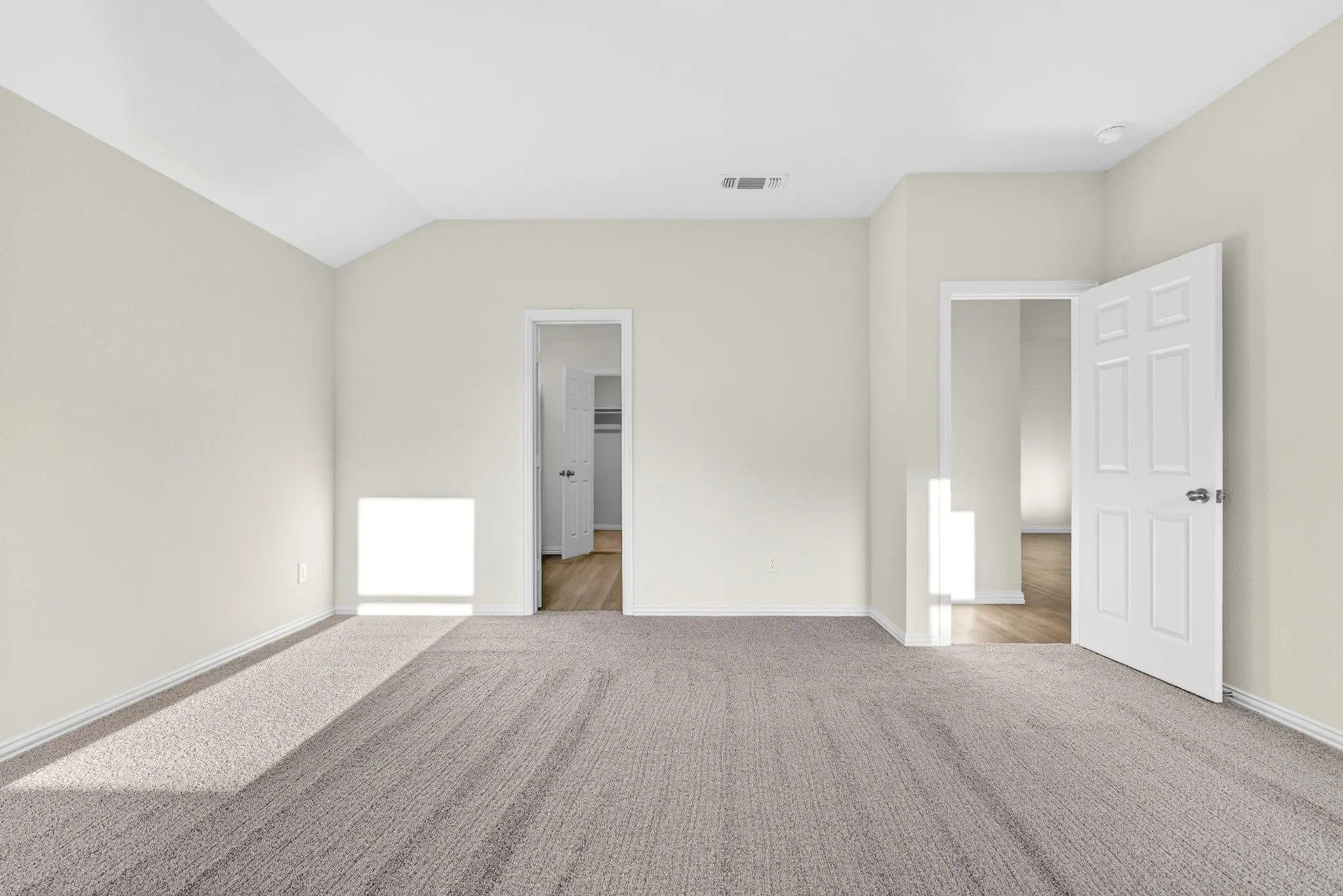 Carpeted flooring, vaulted ceiling, white interior doors, and neutral wall paint