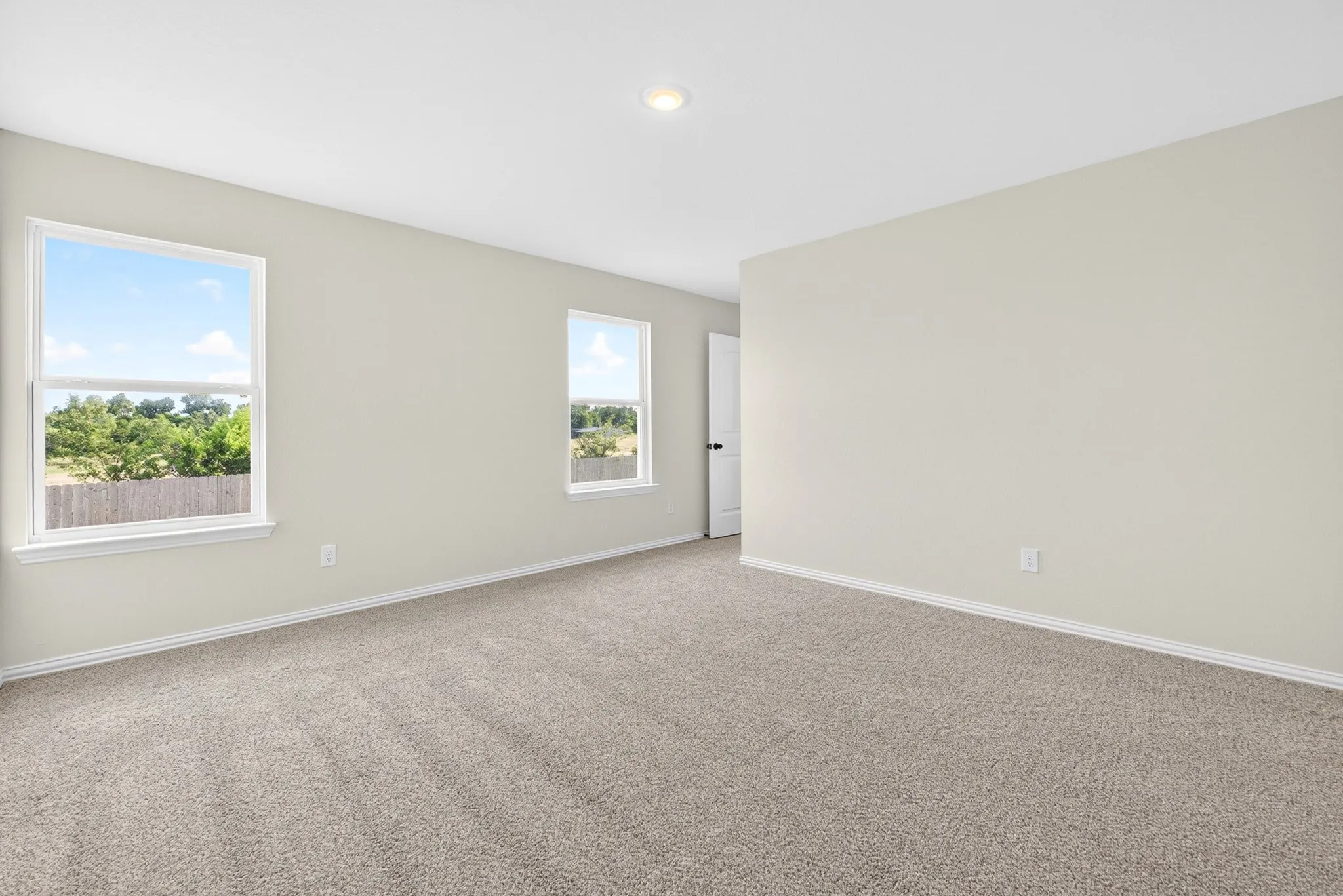 Neutral wall paint, two windows, recessed ceiling lighting, and carpet flooring
