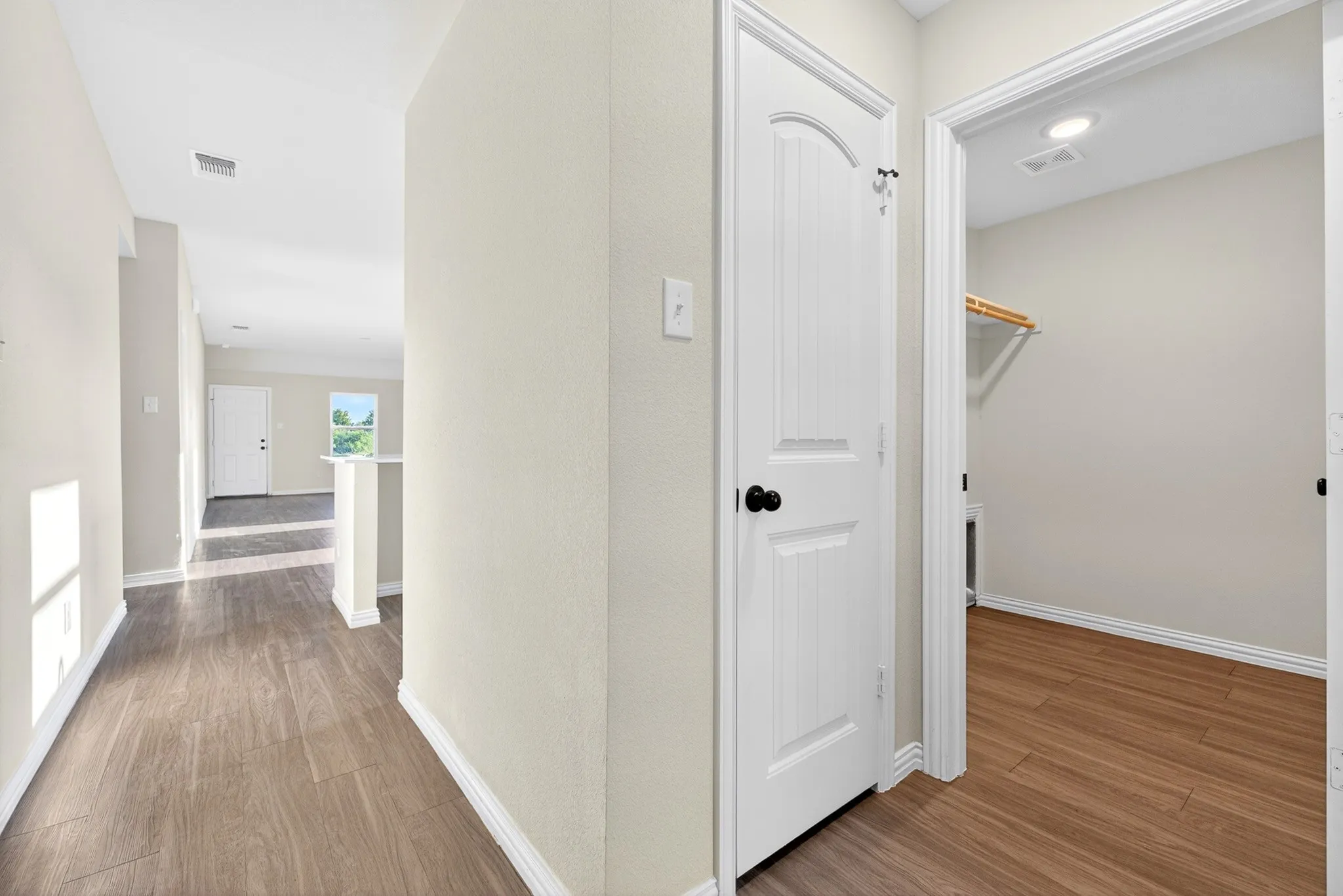 Wood-finish flooring, recessed lighting, white interior doors, and a built-in closet shelf