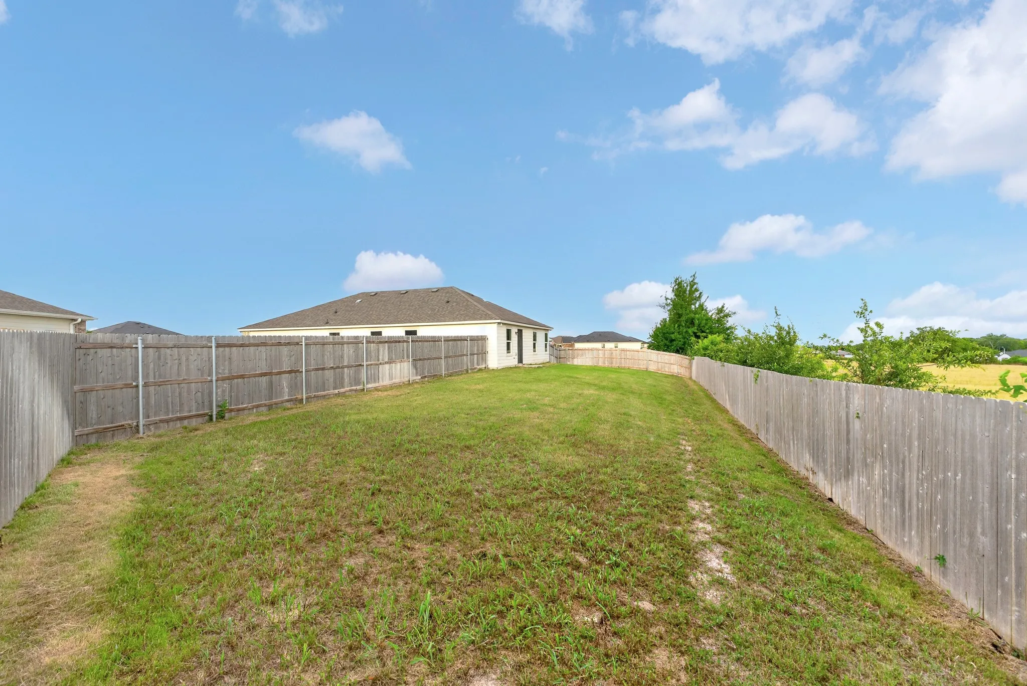 Expansive backyard featuring a privacy fence and a manicured lawn
