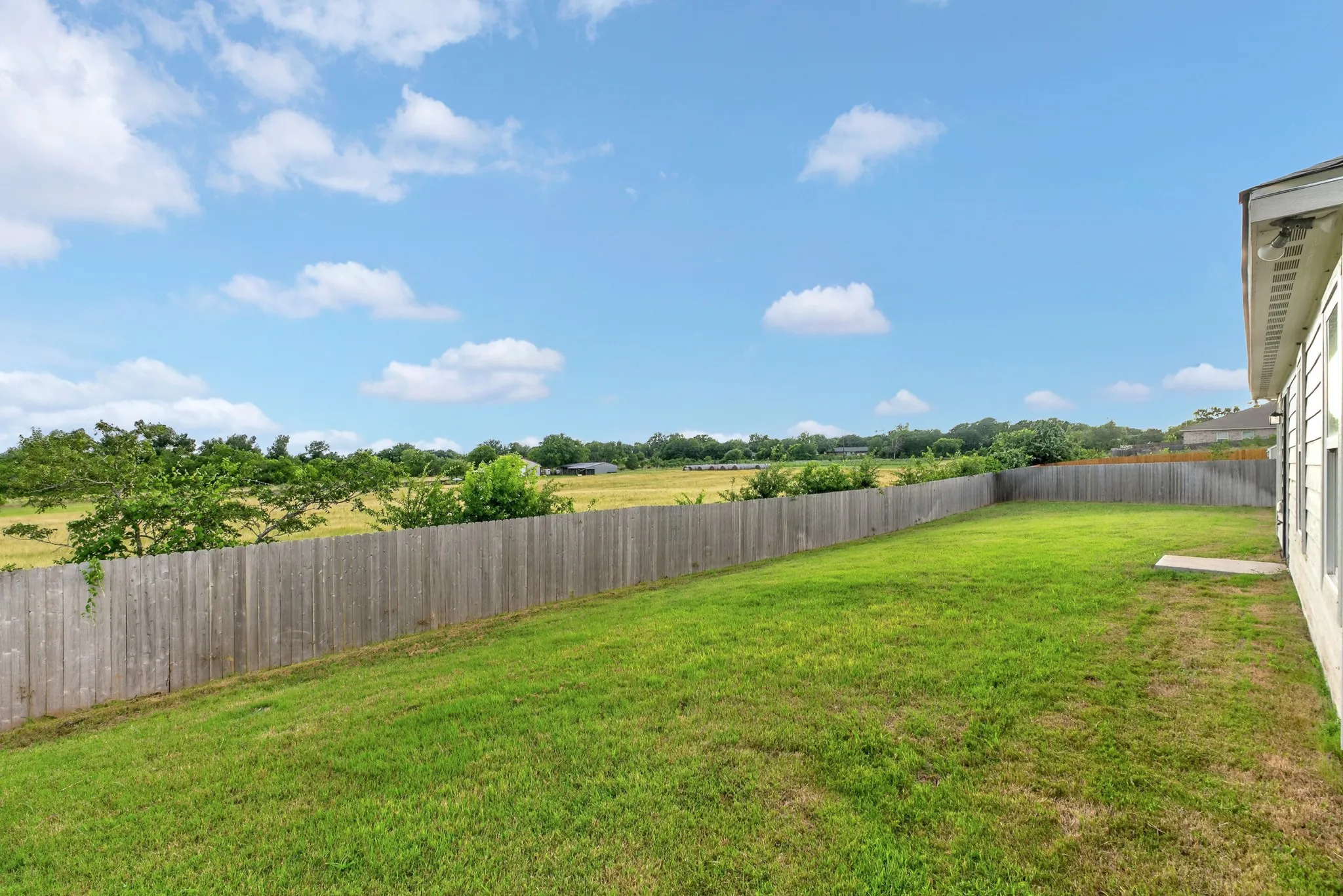 Expansive green lawn with a wood privacy fence
