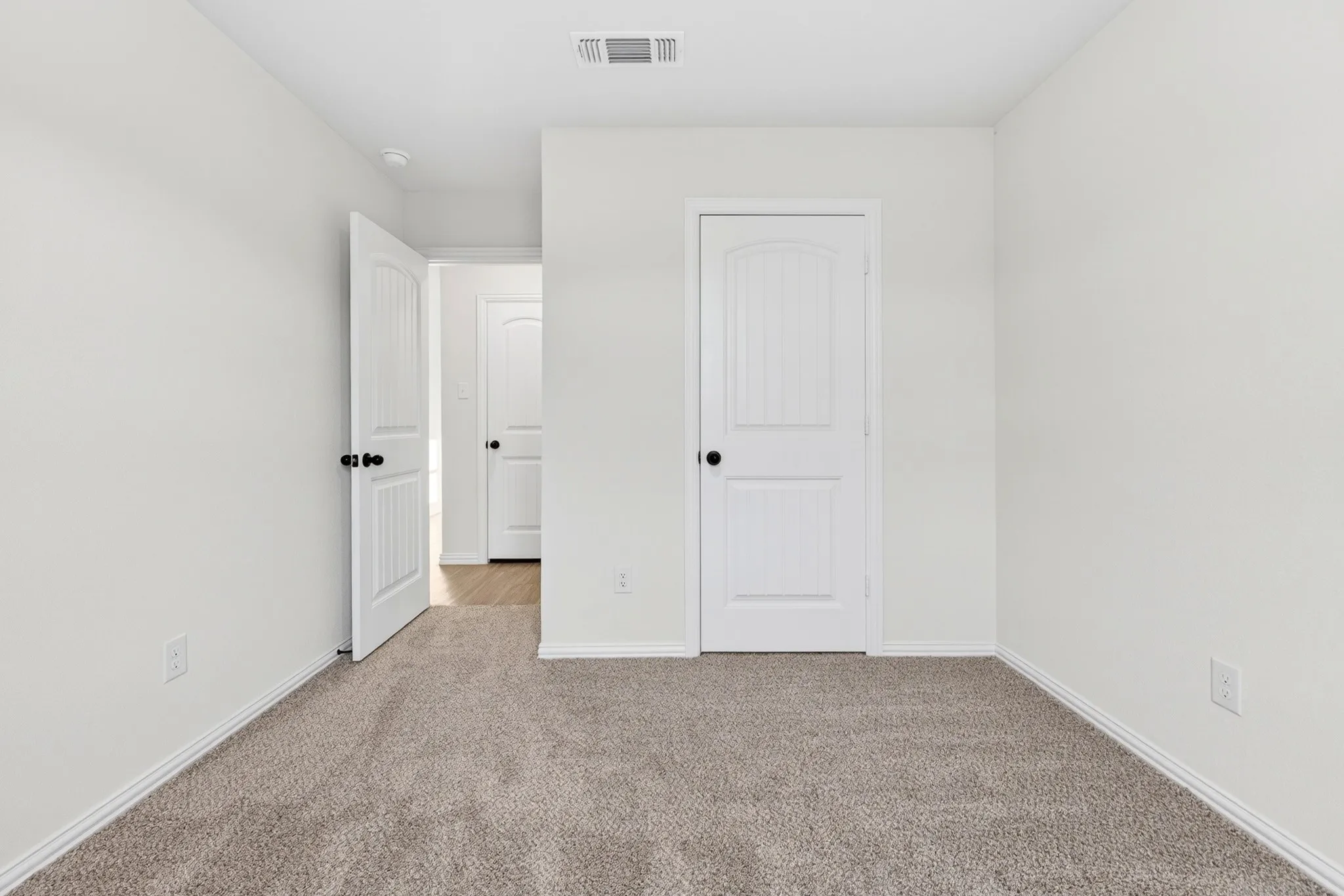 Soft neutral-toned carpeting, light-colored walls, and white paneled doors