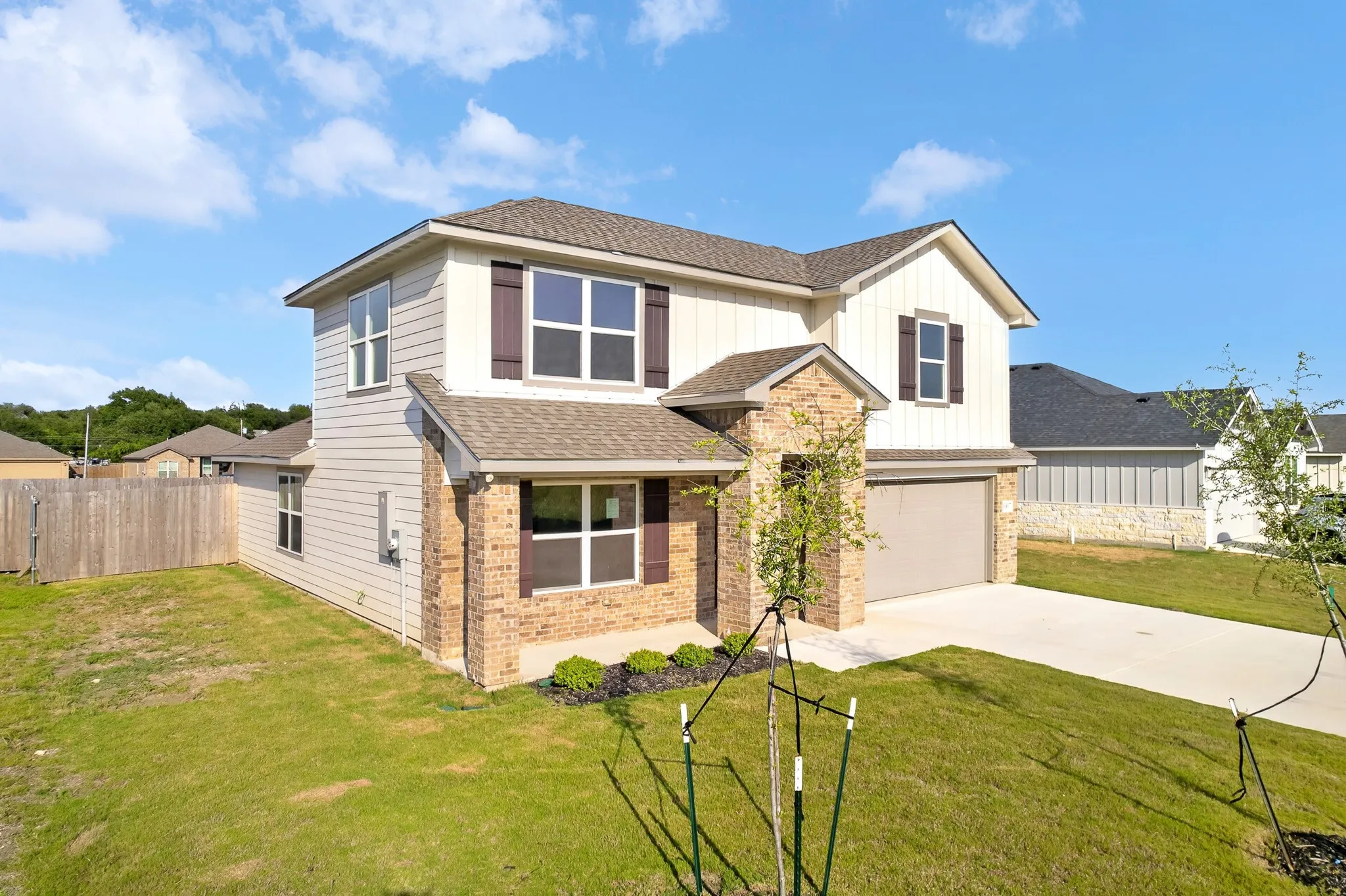 Two-story residence featuring a combination of brick and siding facade, a two-car garage, and a concrete driveway
