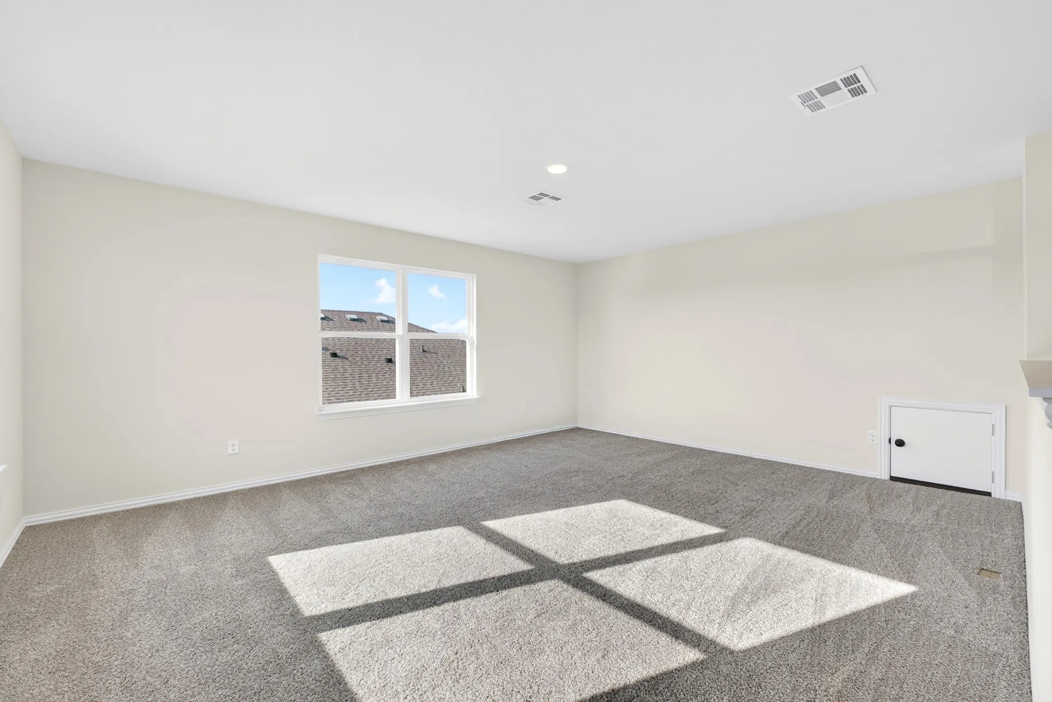 Carpeted room with a single window, recessed ceiling lighting, and a white access panel