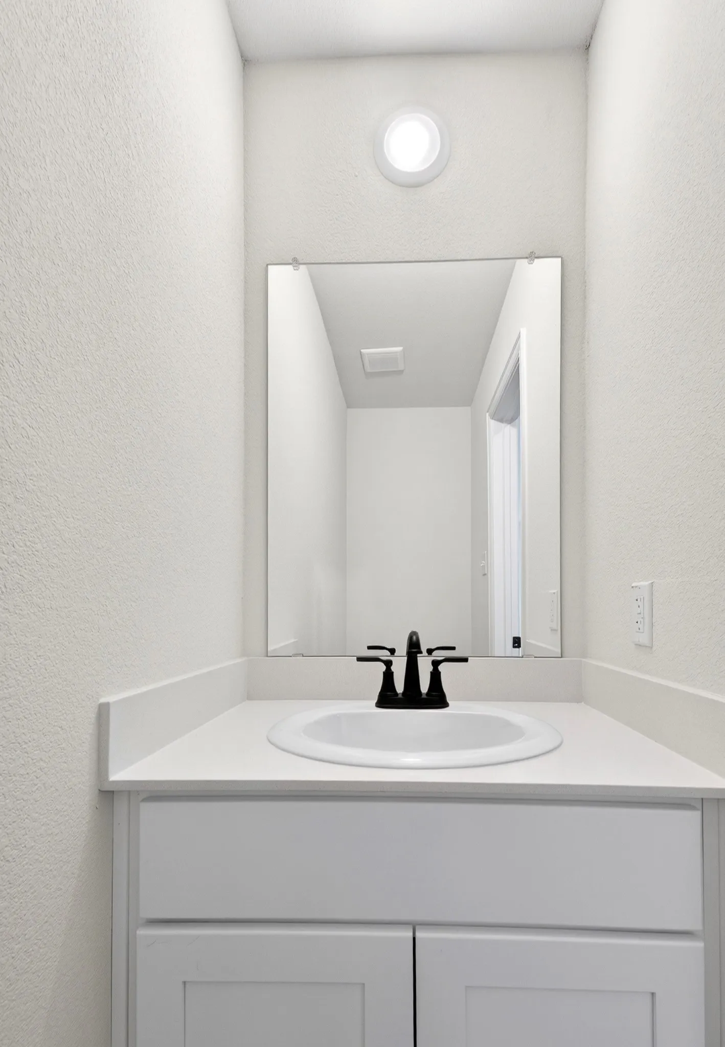 White vanity with an integrated sink, black two-handle faucet, and white countertop