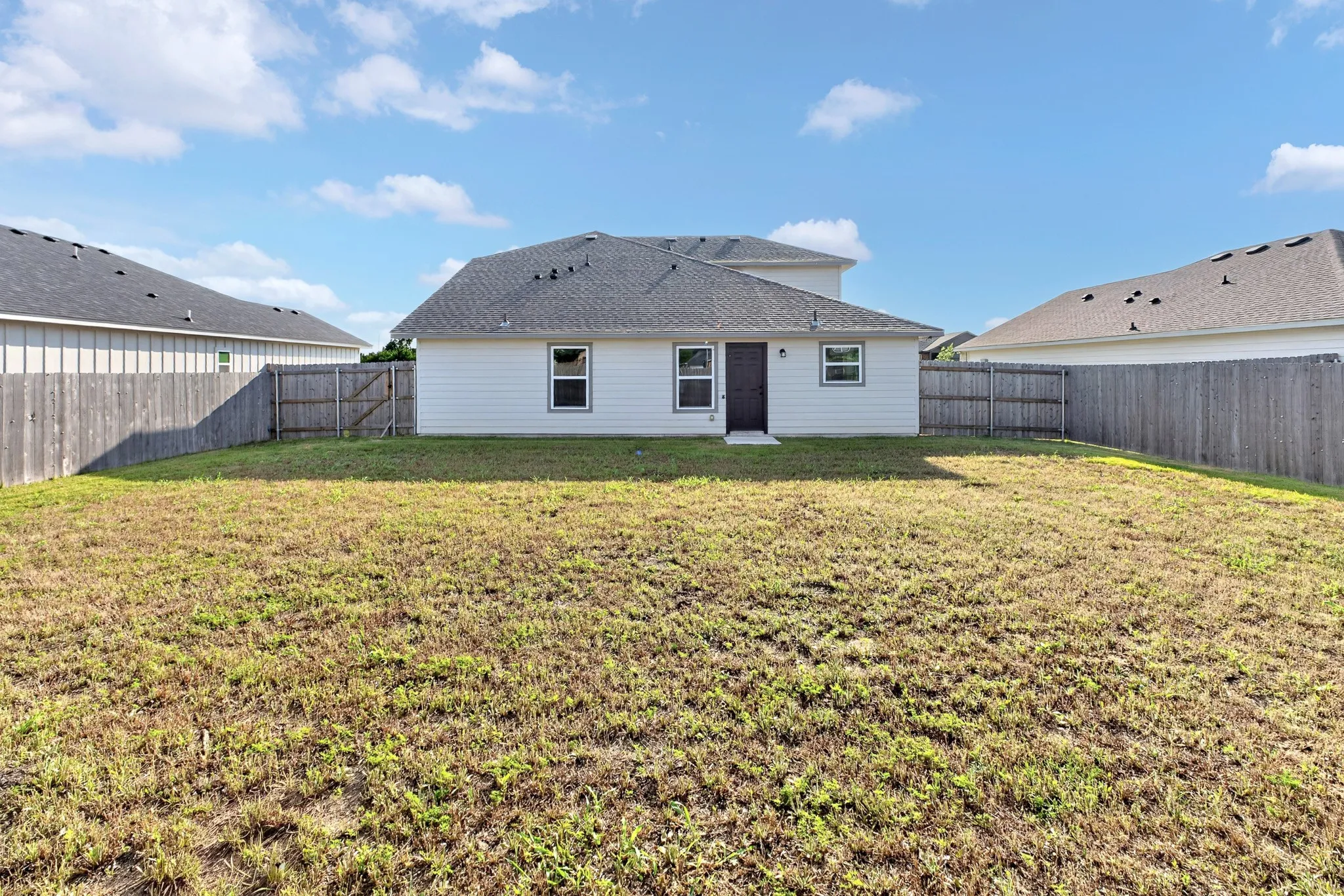 Spacious backyard with mature landscaping and level grounds, bordered by residential fencing