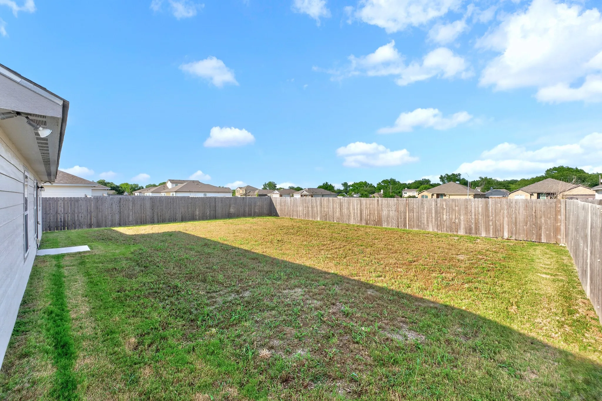 Expansive backyard featuring a full perimeter privacy fence and a manicured lawn