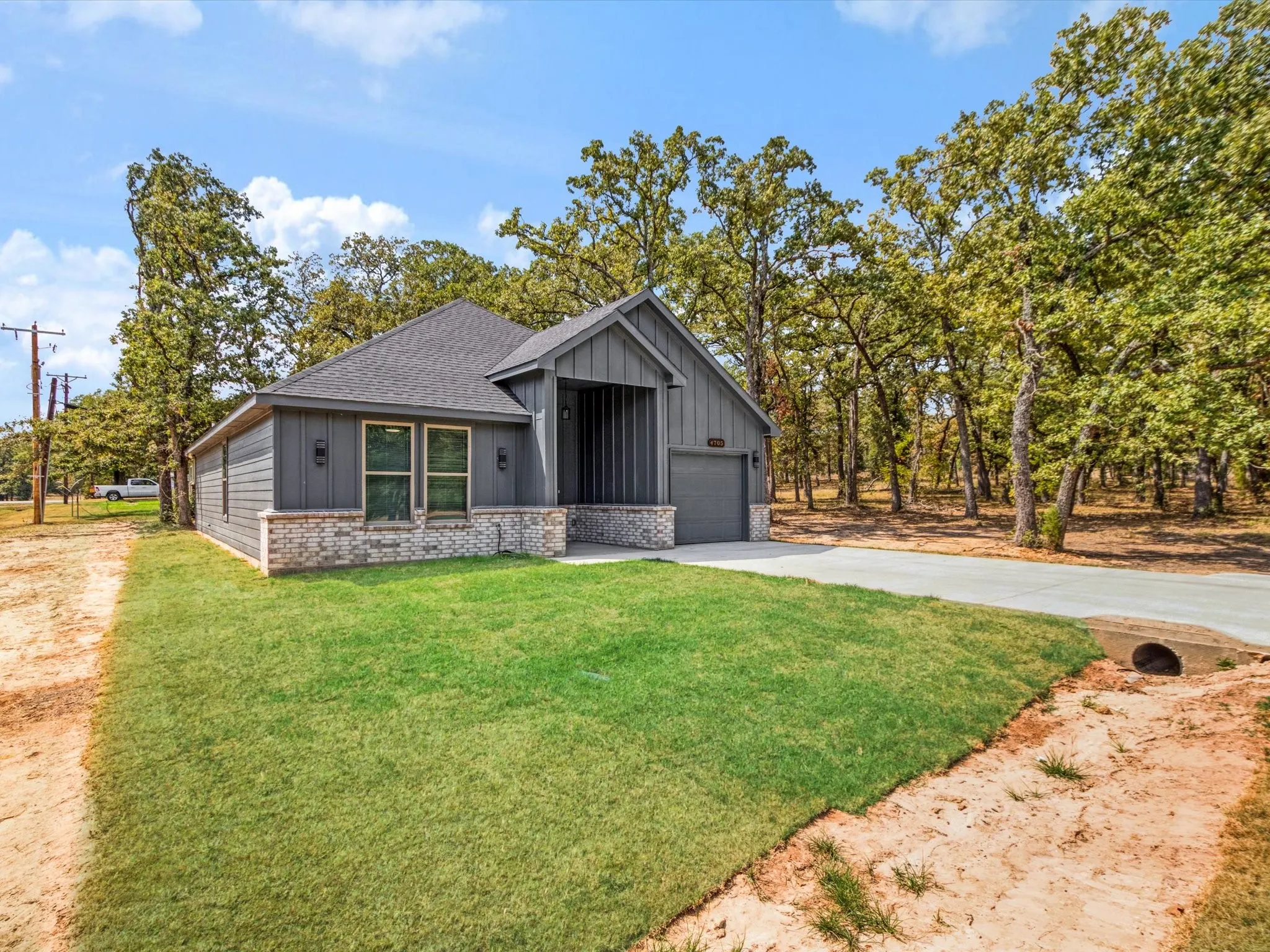 Modern exterior with vertical and horizontal siding, brick accents, a gabled roof, and an attached garage