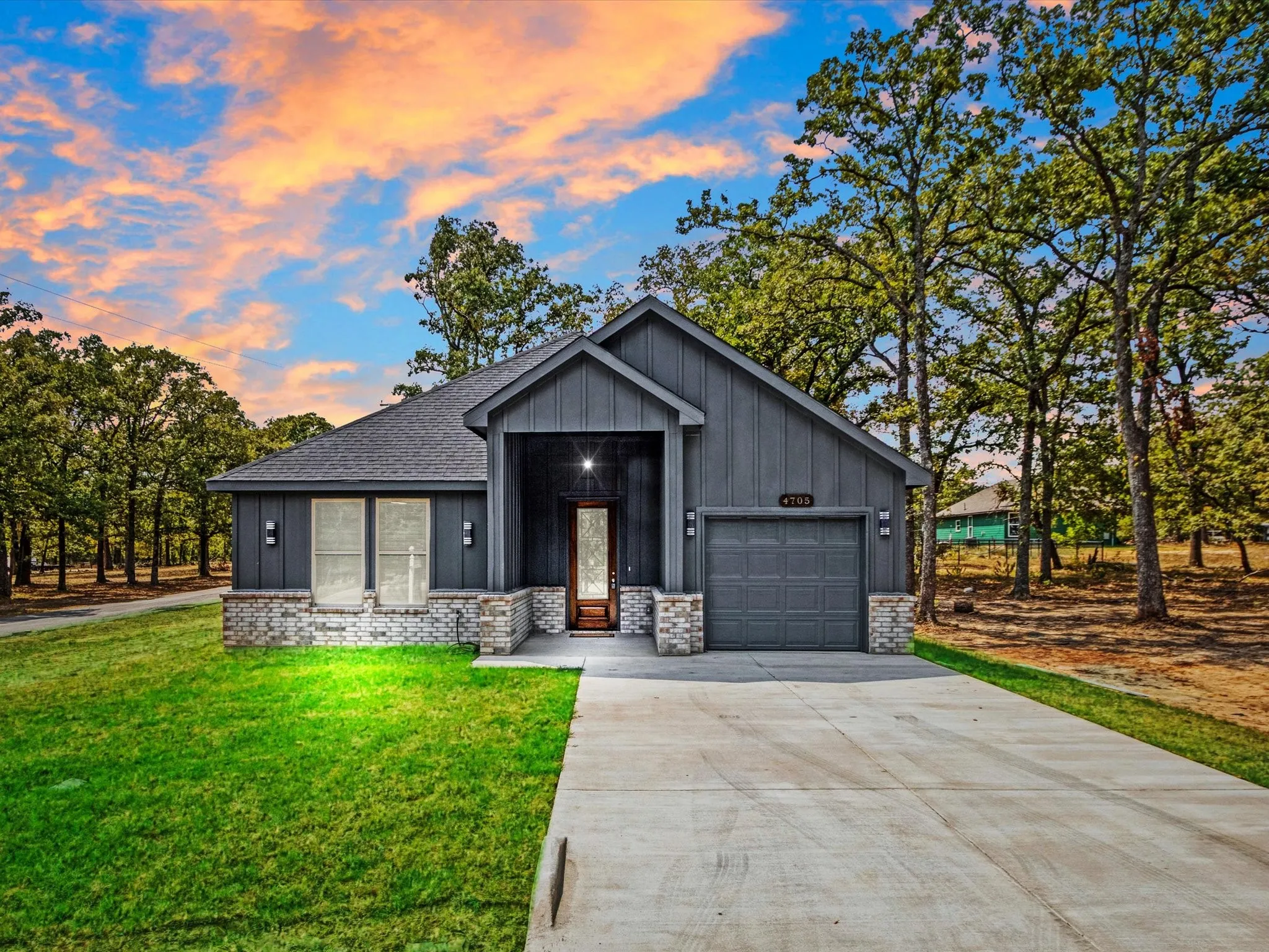 Modern exterior featuring board and batten siding with brick accents, an integrated garage, and a concrete driveway