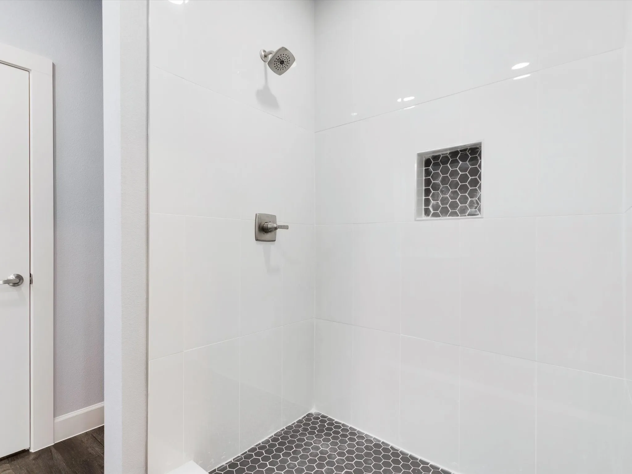 Shower with white subway tile, a built-in hexagonal tile niche, and a brushed nickel shower head