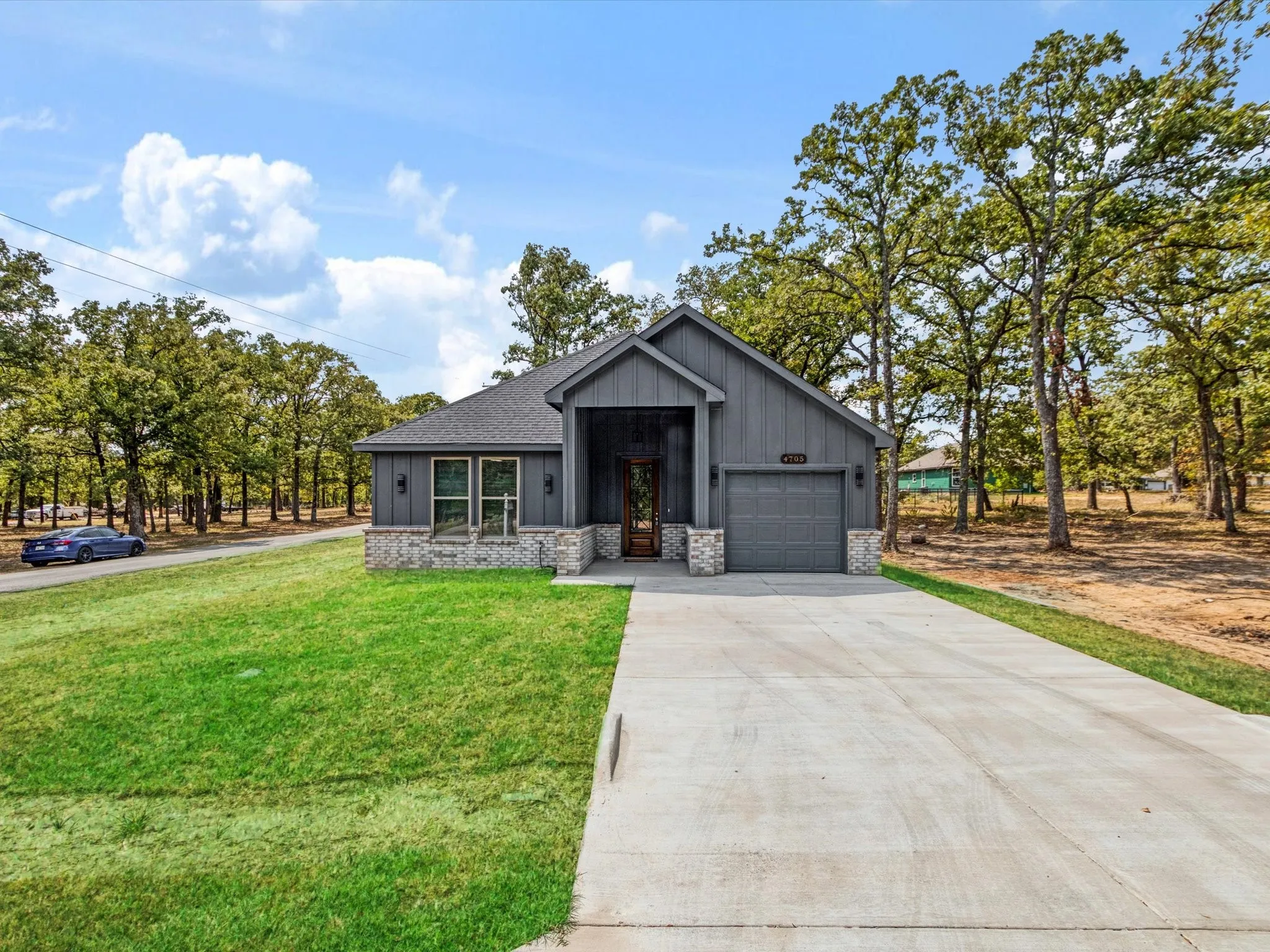 Modern exterior siding with a covered entry, attached garage, stone accents, and a concrete driveway