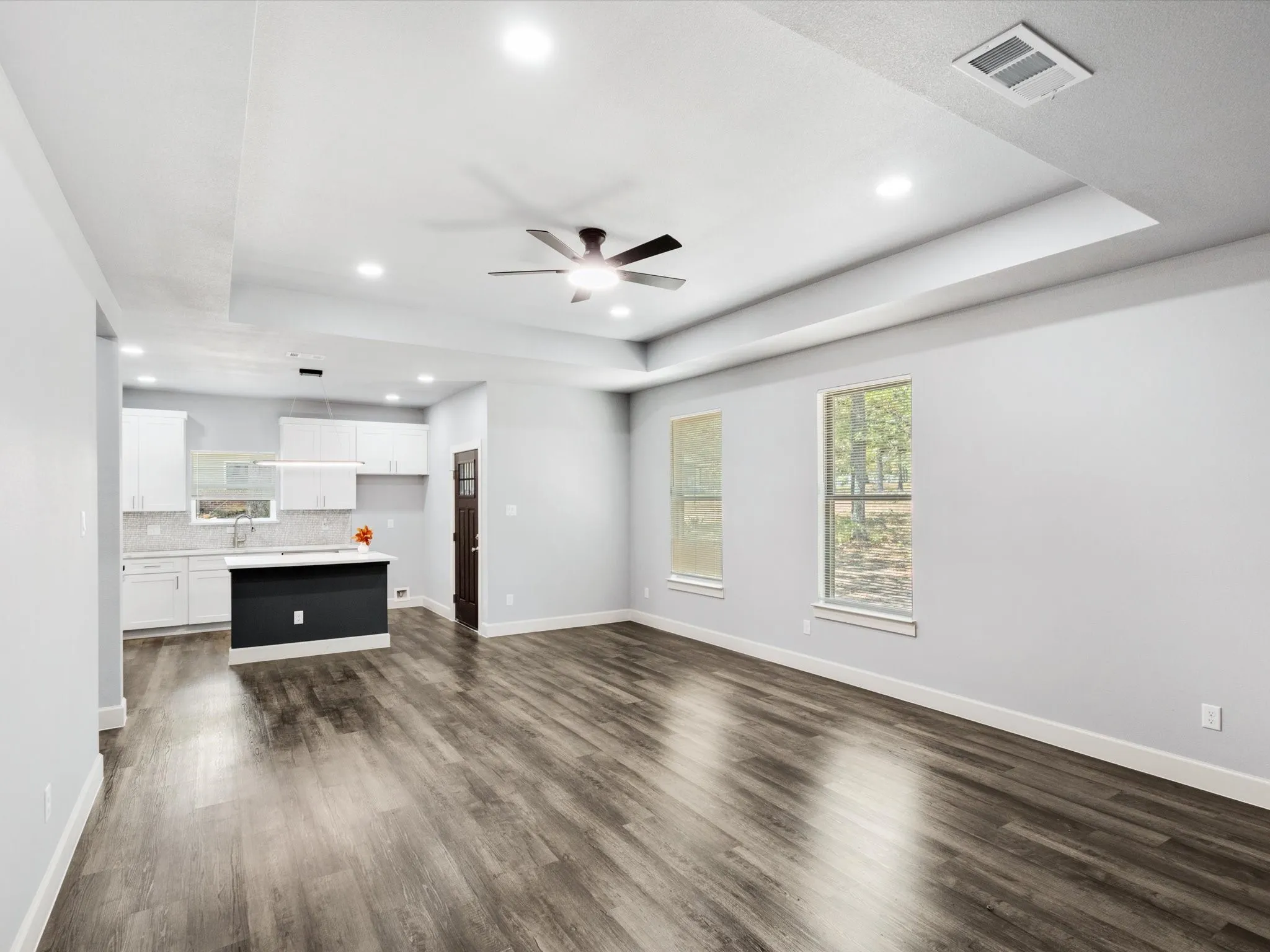 Spacious open-concept living area featuring wood-finish flooring, recessed lighting, and a modern ceiling fan