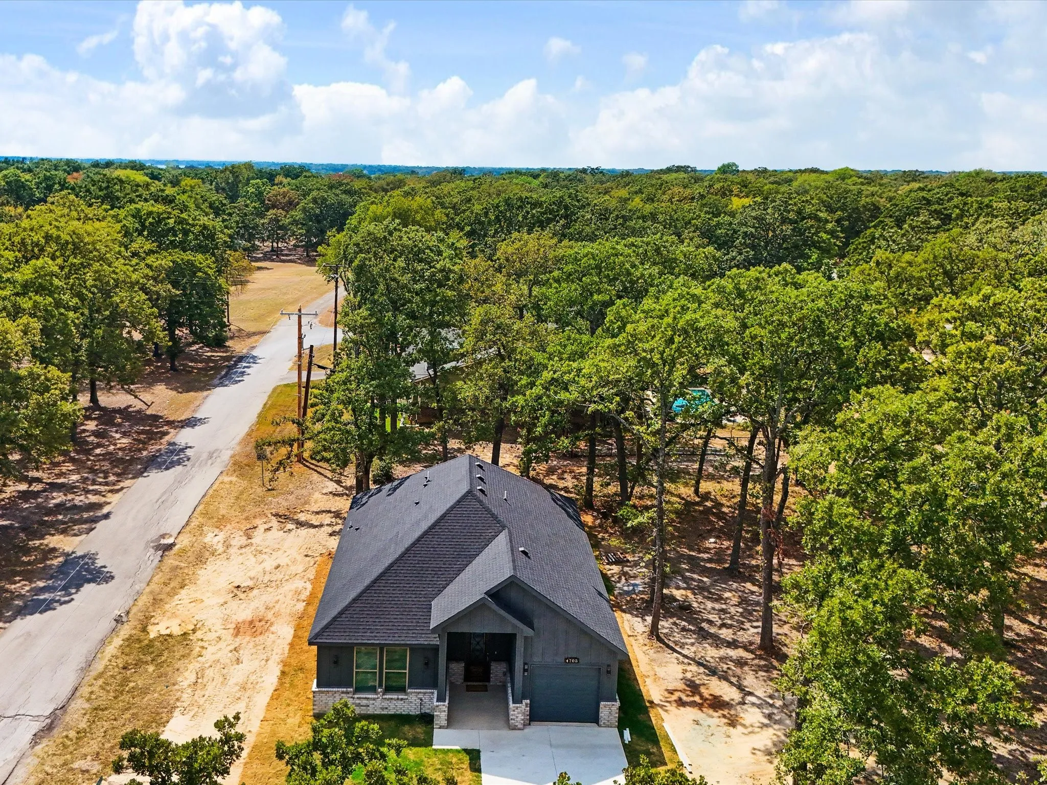 Modern construction featuring a dark shingle roof, gray siding, and stone accents