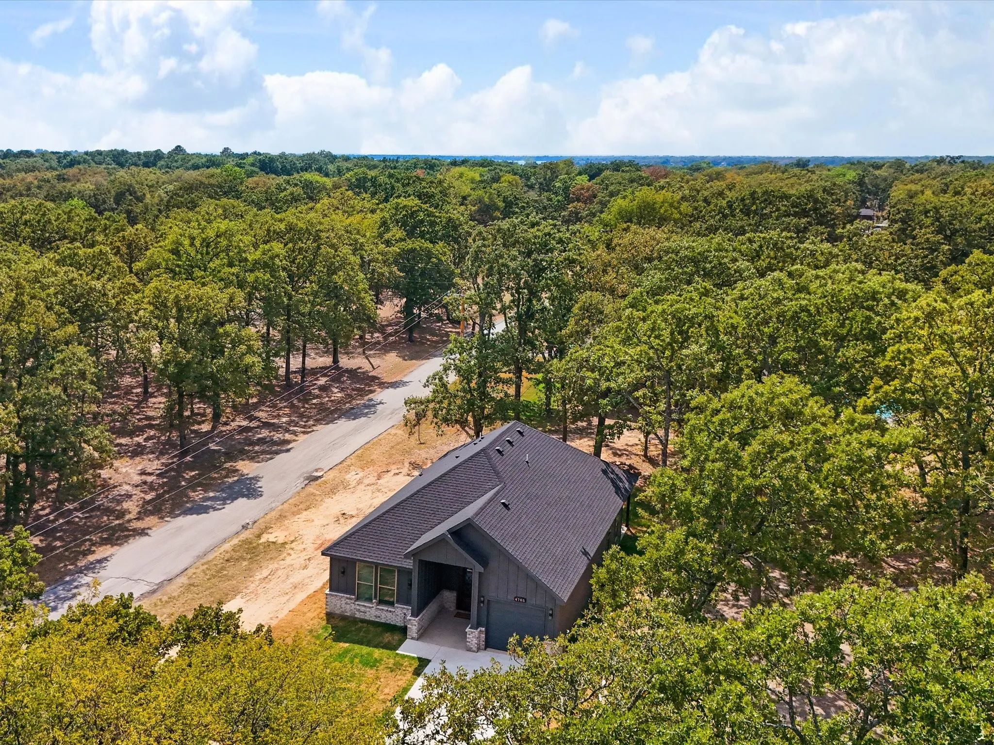Contemporary-style residence with a dark gray facade, stone accents, and a dark shingle roof