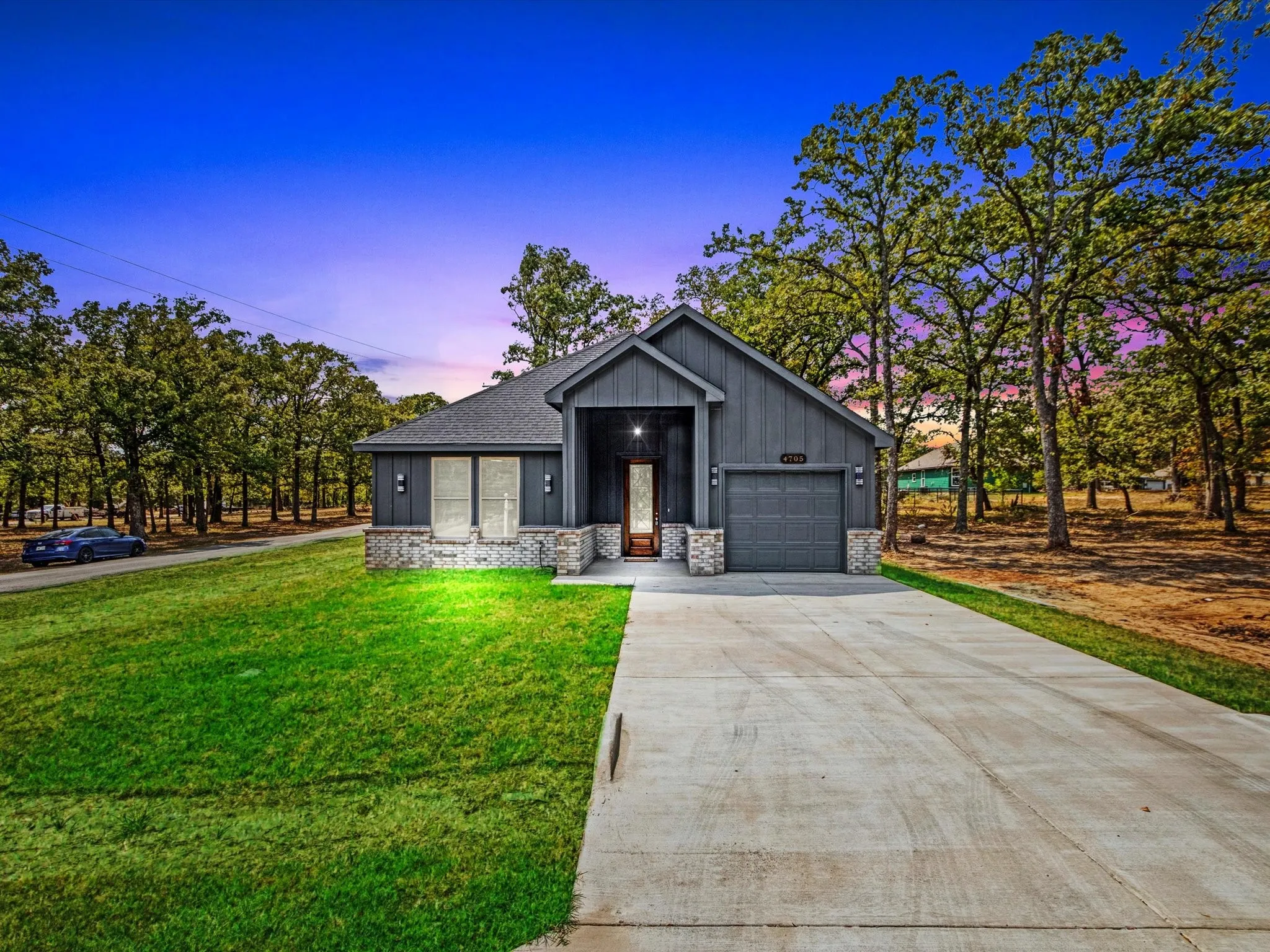 Contemporary exterior with dark siding, stone accents, attached garage, and a concrete driveway