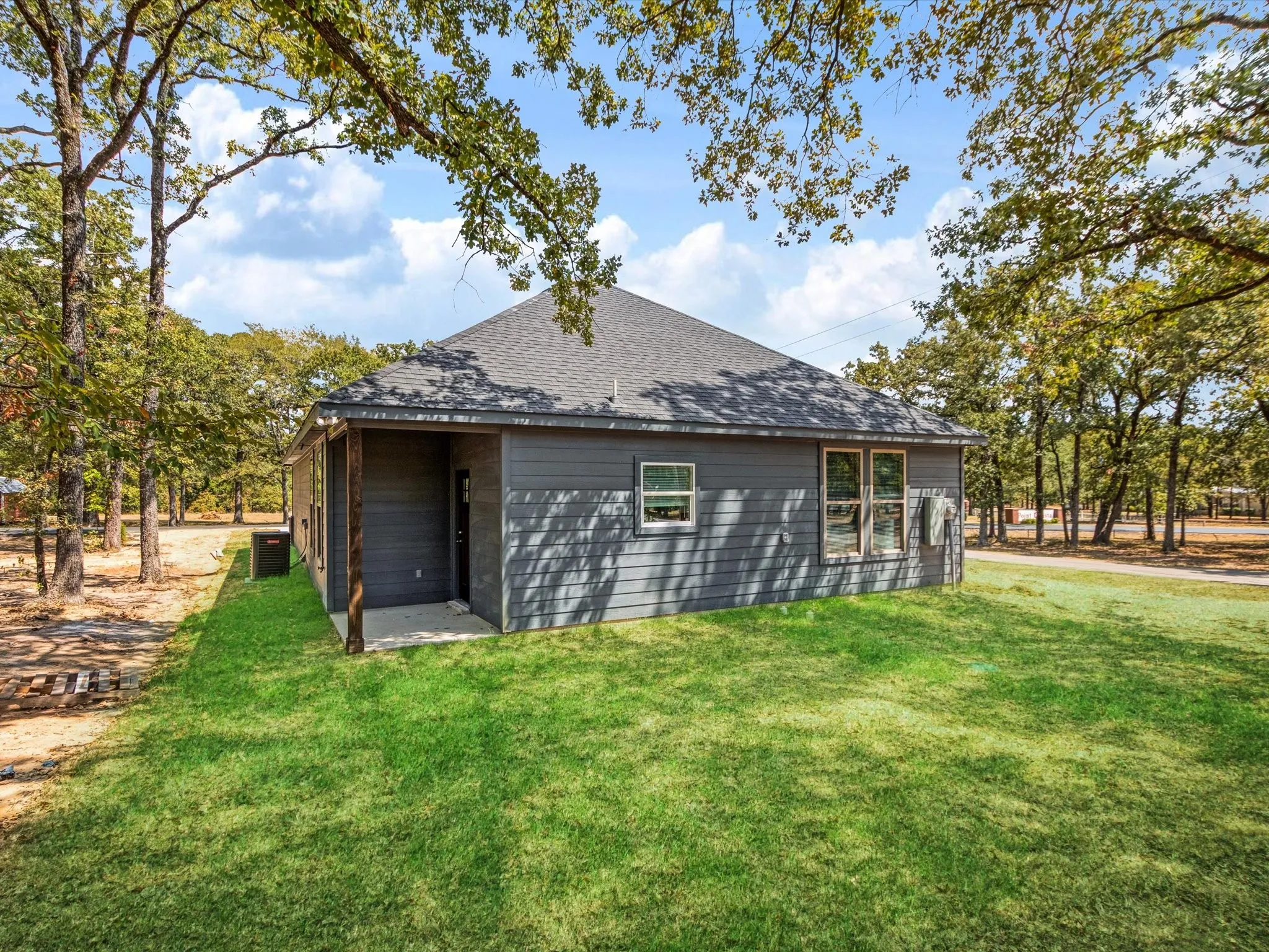 Exterior with gray siding, dark shingle roof, and a concrete patio