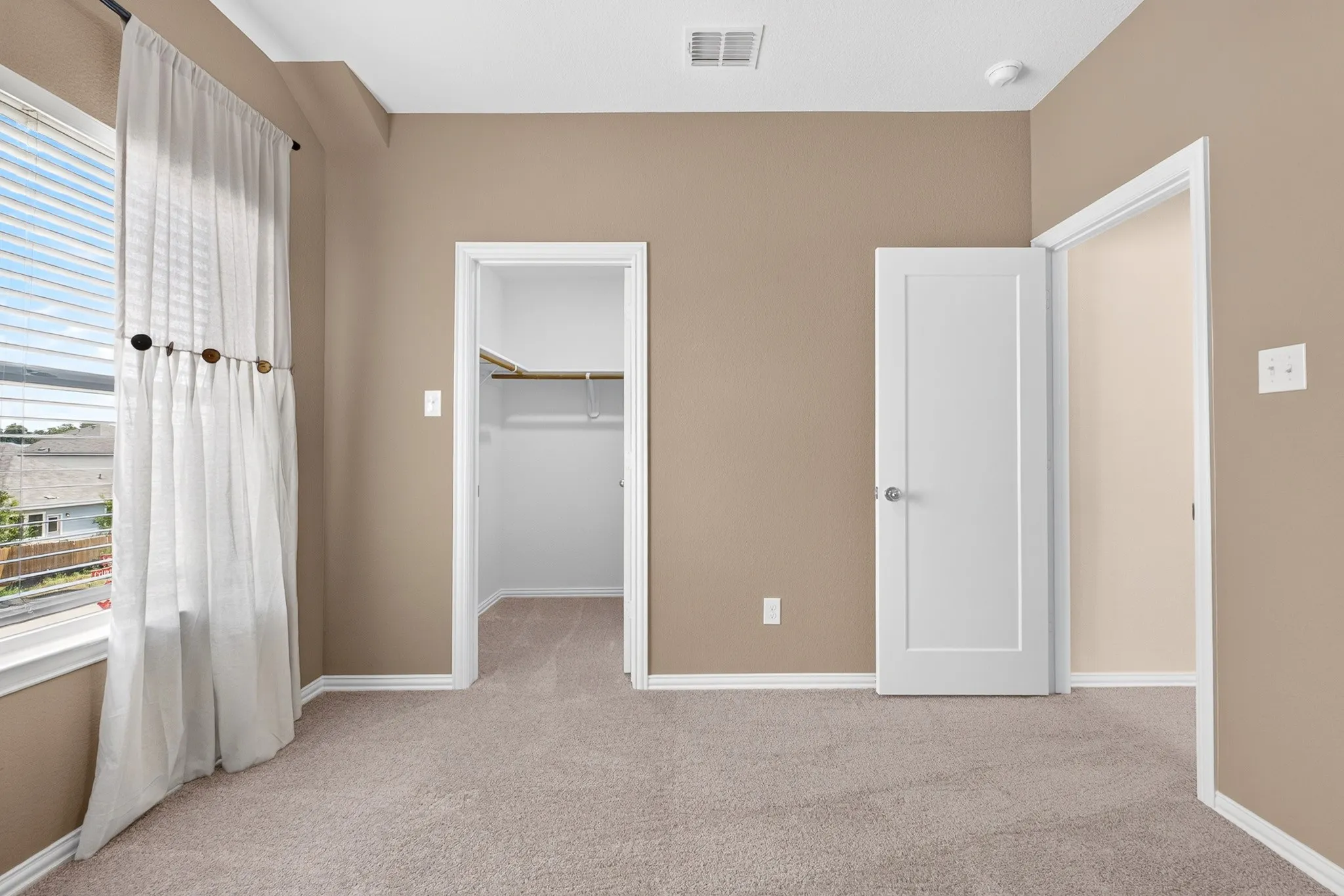 Plush carpet flooring, light neutral wall color, white trim, and a window with blinds