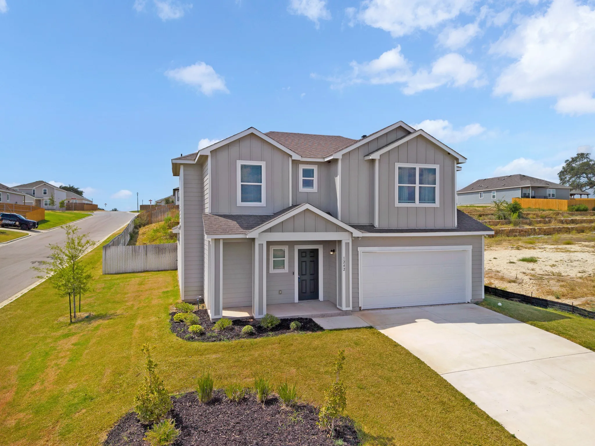 Contemporary two-story exterior with light gray siding, a covered entry, an attached garage, and a concrete driveway
