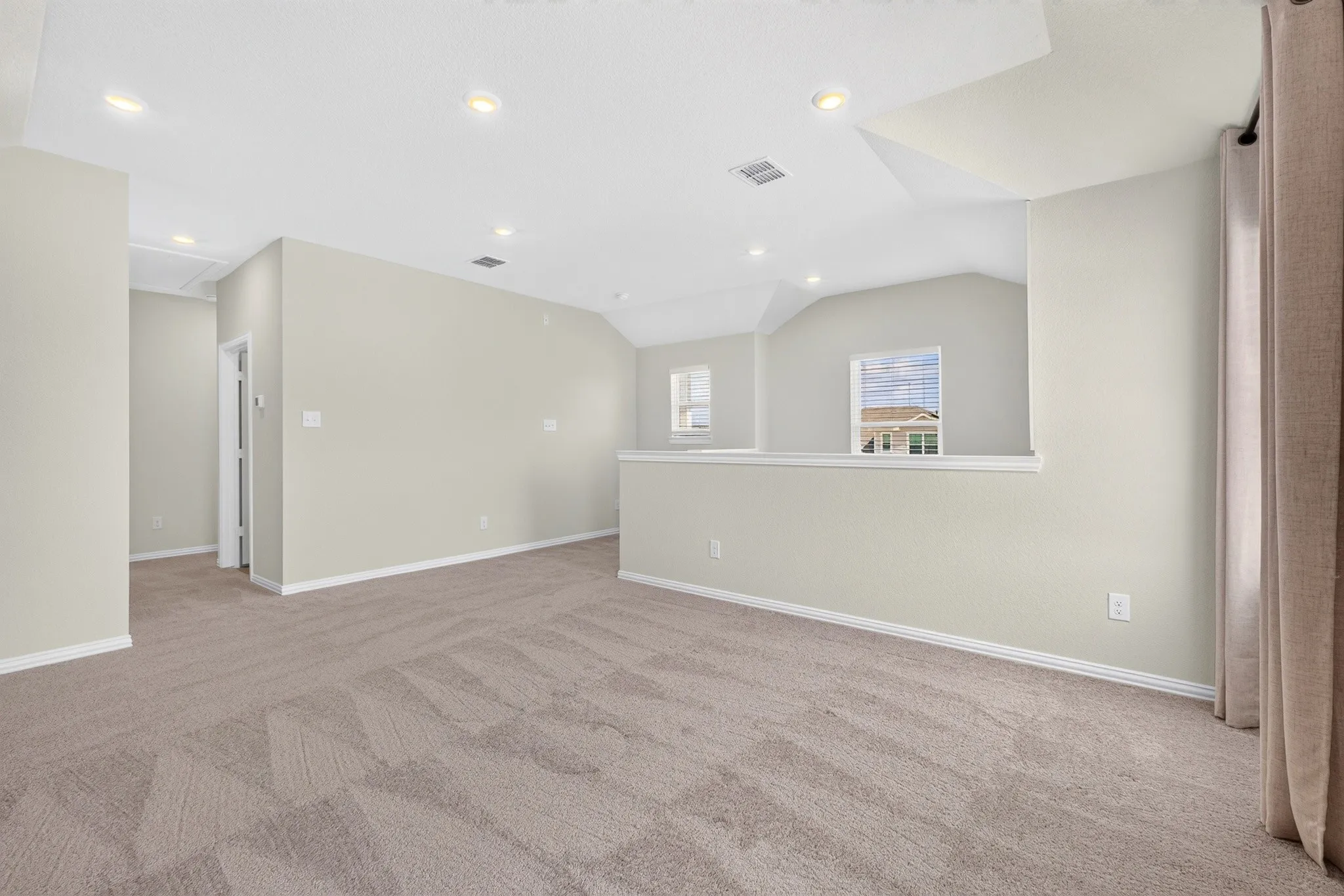 Carpeted secondary living space featuring a tray ceiling, recessed lighting, and half-wall partitioning