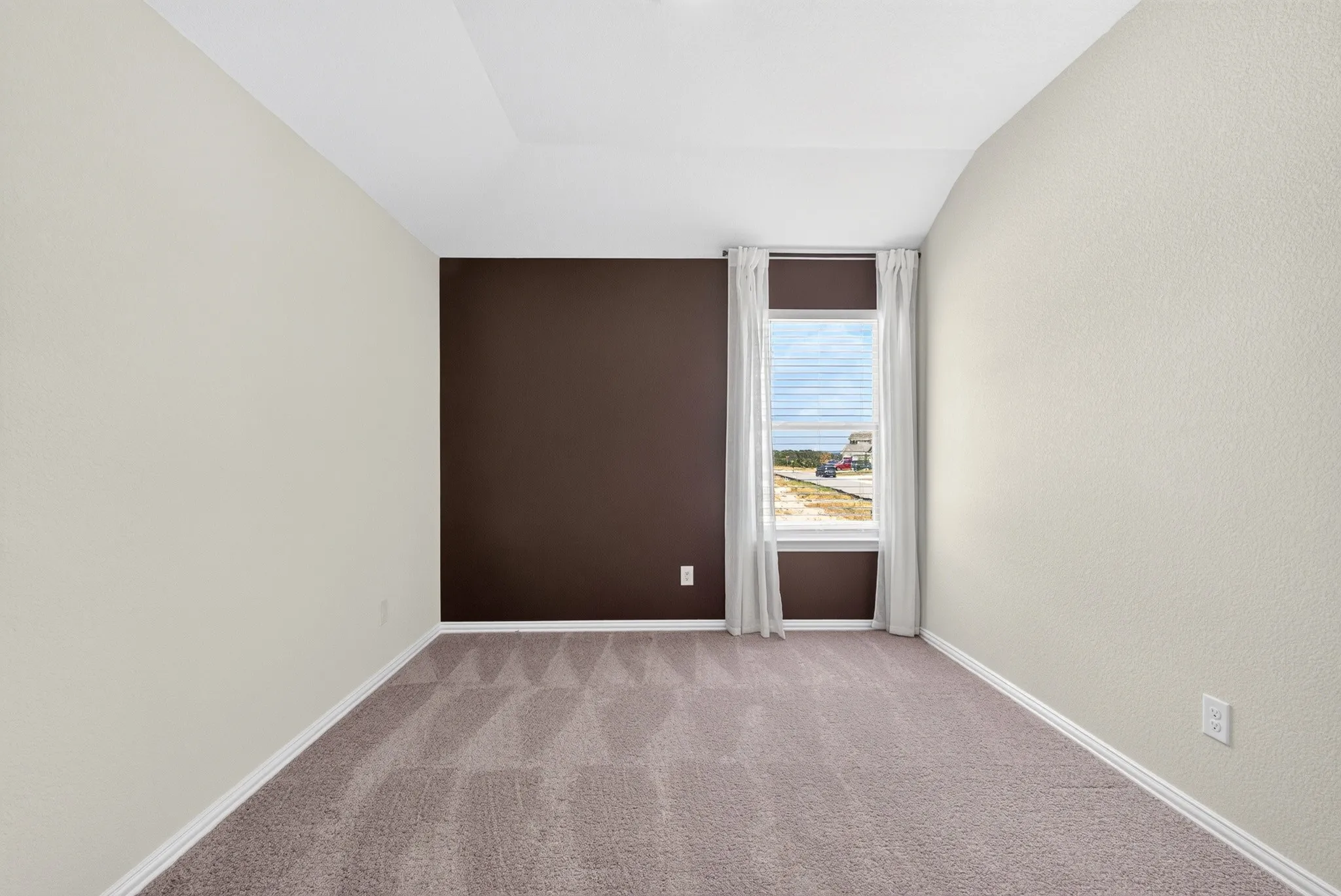 Window with blinds and drapes, tray ceiling, and textured walls
