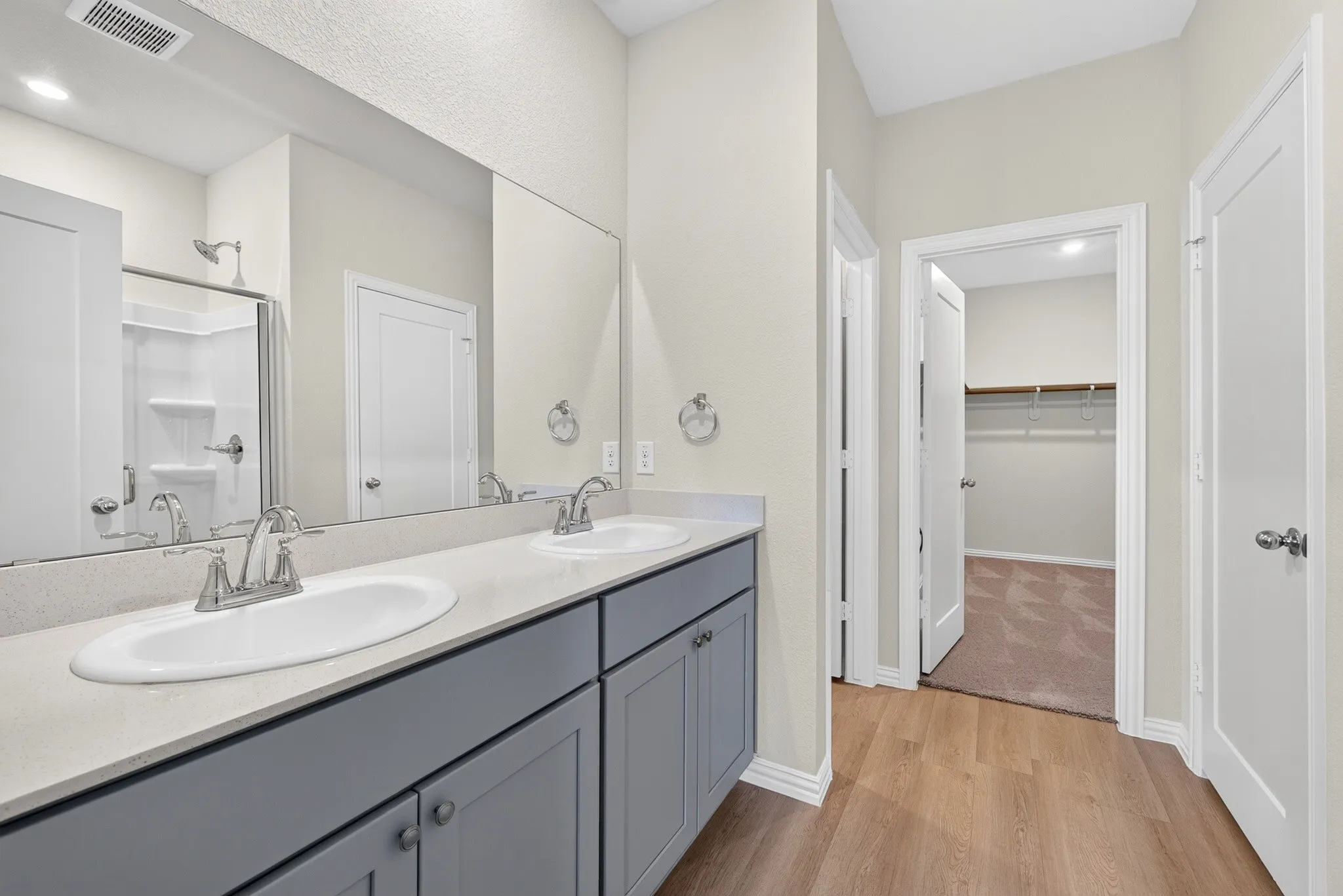 Dual vanity with undermount sinks, gray shaker-style cabinetry, and a full-width mirror
