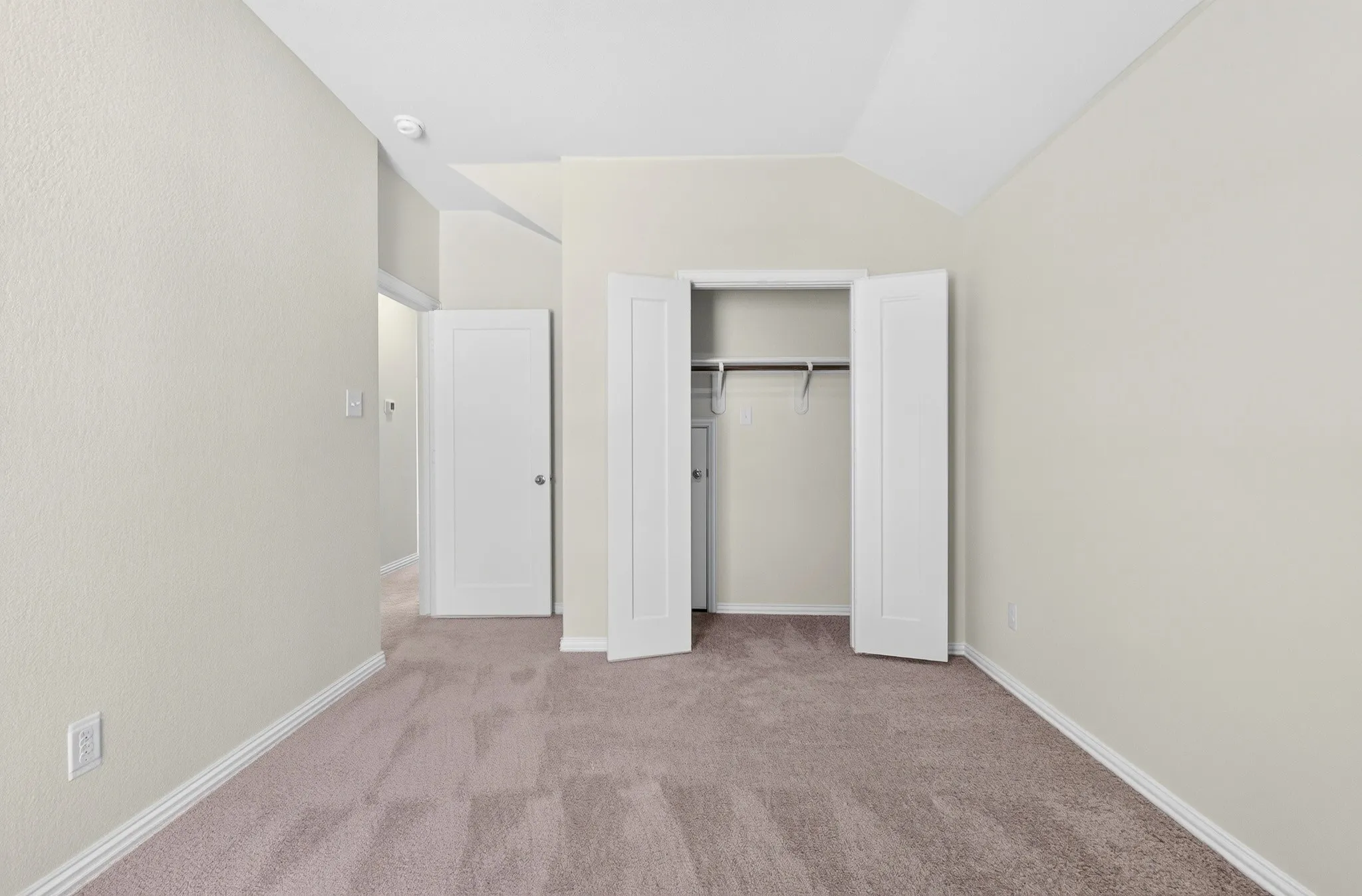 Light neutral wall paint, carpeted flooring, white trim, and a built-in closet with hanging rods