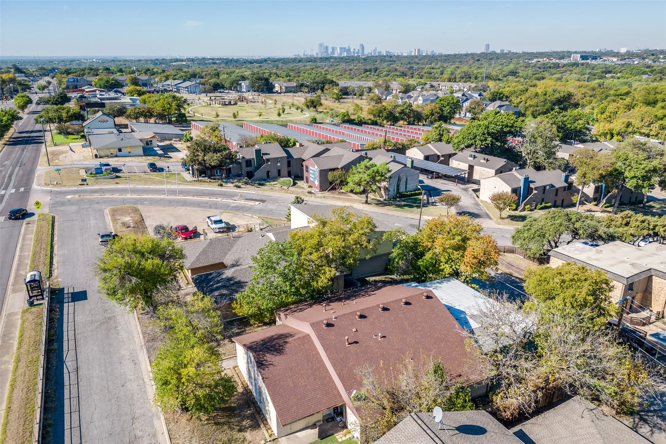 Residential street setting with mature trees and a distant cityscape on the horizon