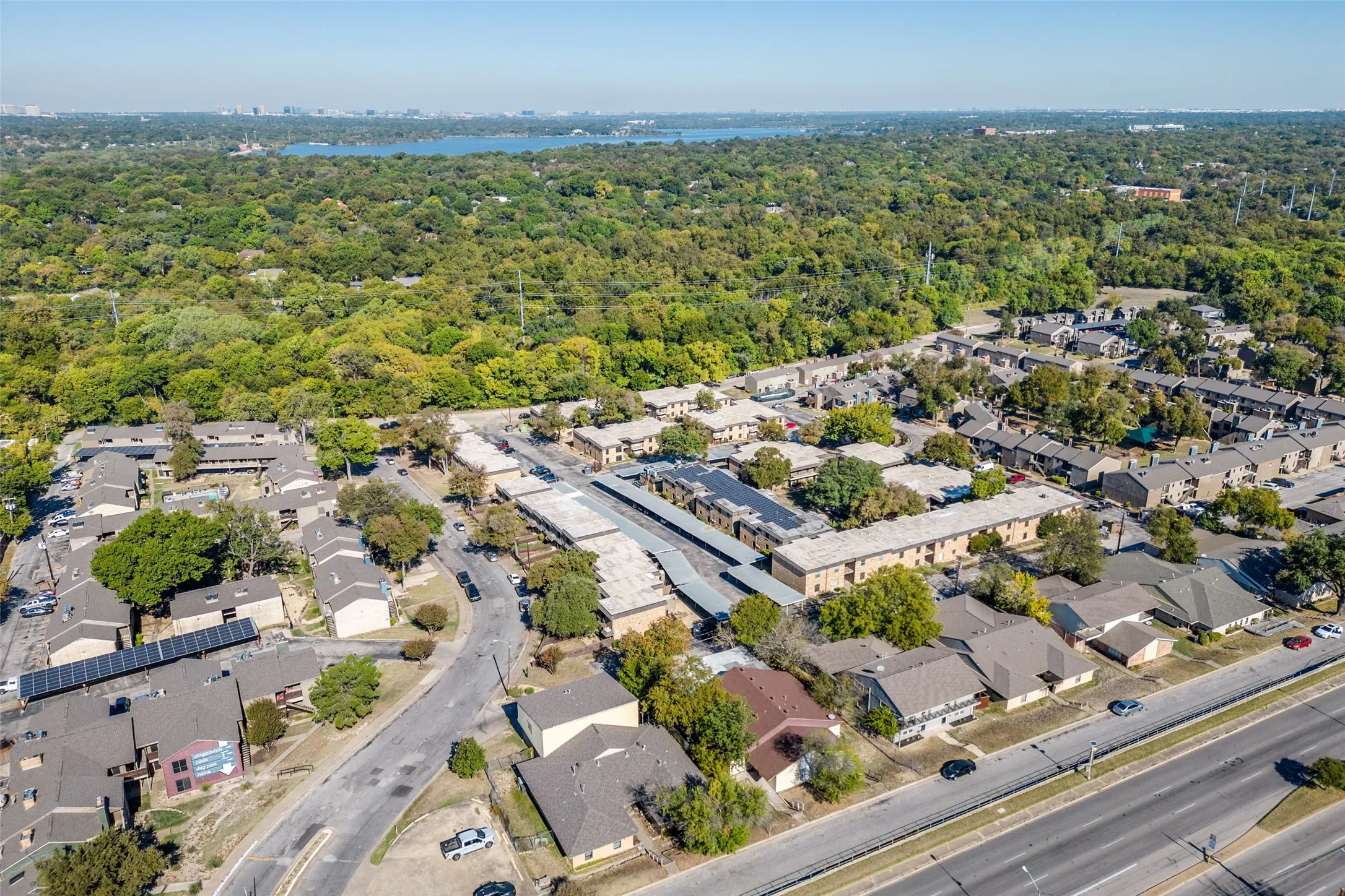 Established residential area with mature trees, paved roadways, and a distant body of water