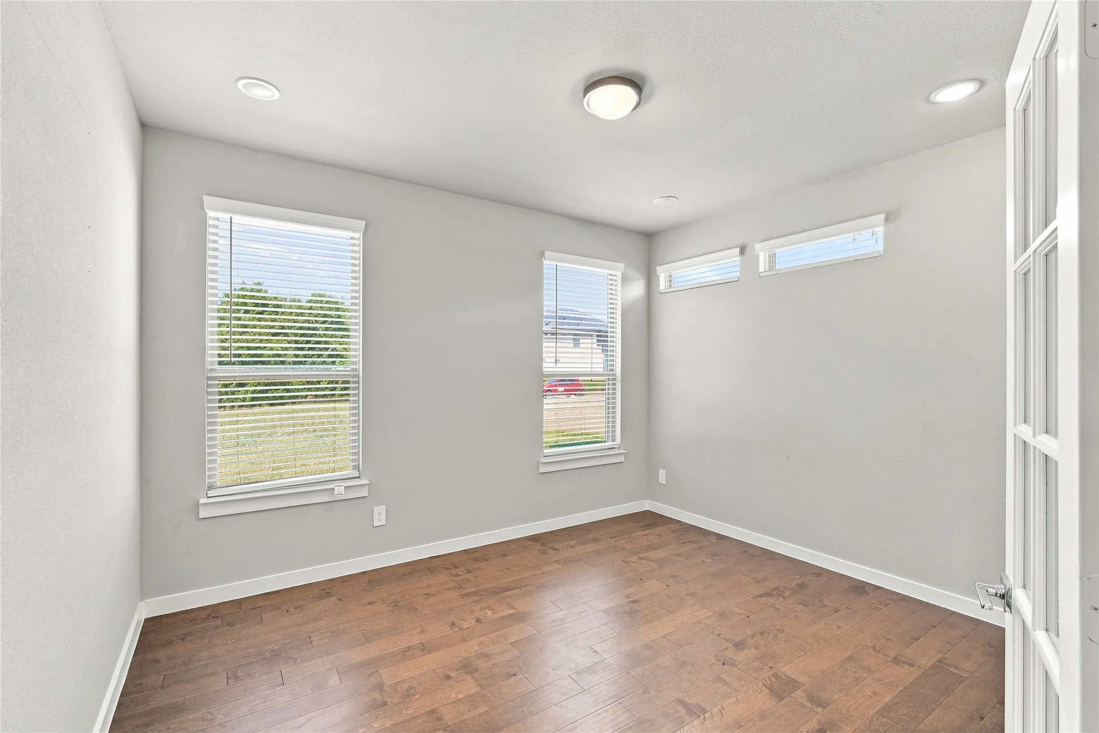Wood-finish flooring, recessed lighting, and multiple windows with blinds