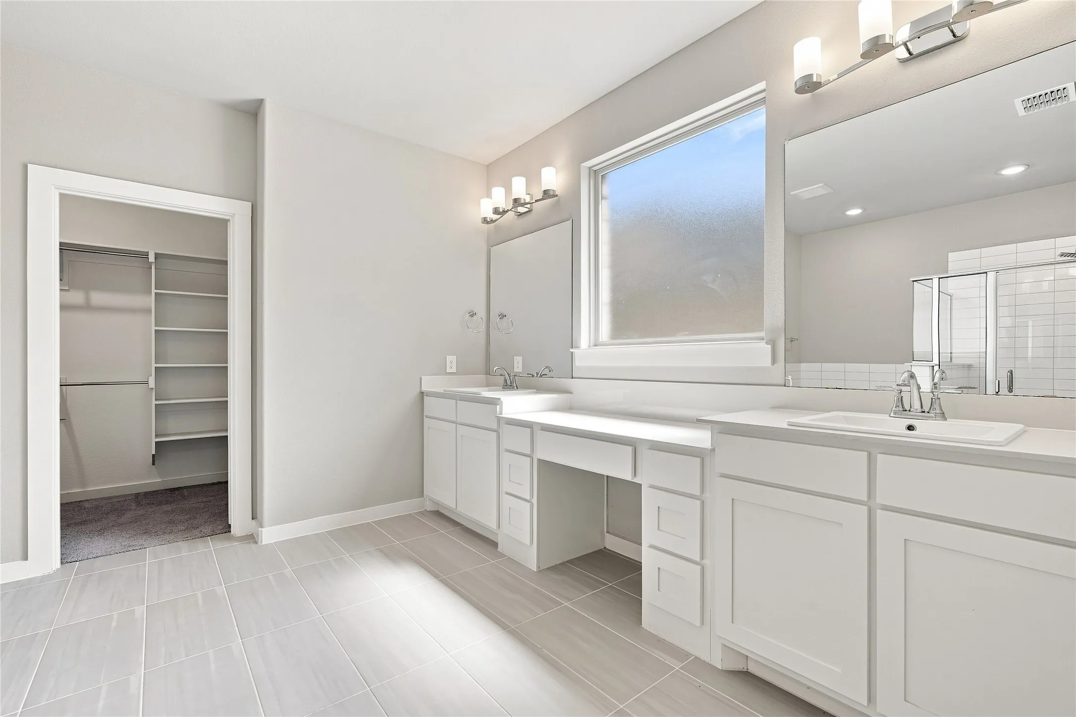 Luxurious primary bathroom featuring dual vanities with quartz countertops, white cabinetry with ample storage, vessel sinks, and polished chrome fixtures