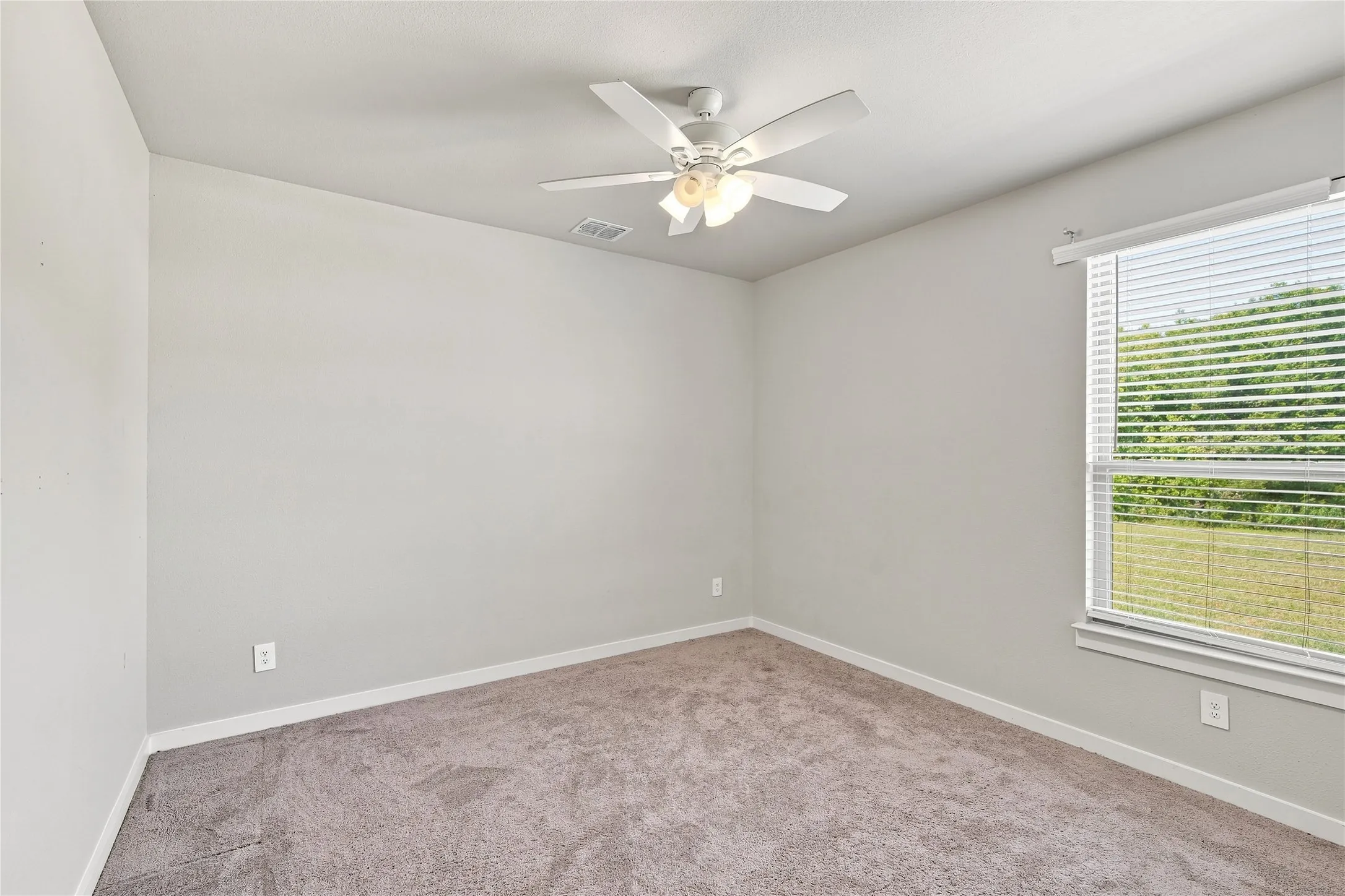 Room with carpeted flooring, a window with blinds, and a ceiling fan with integrated lighting